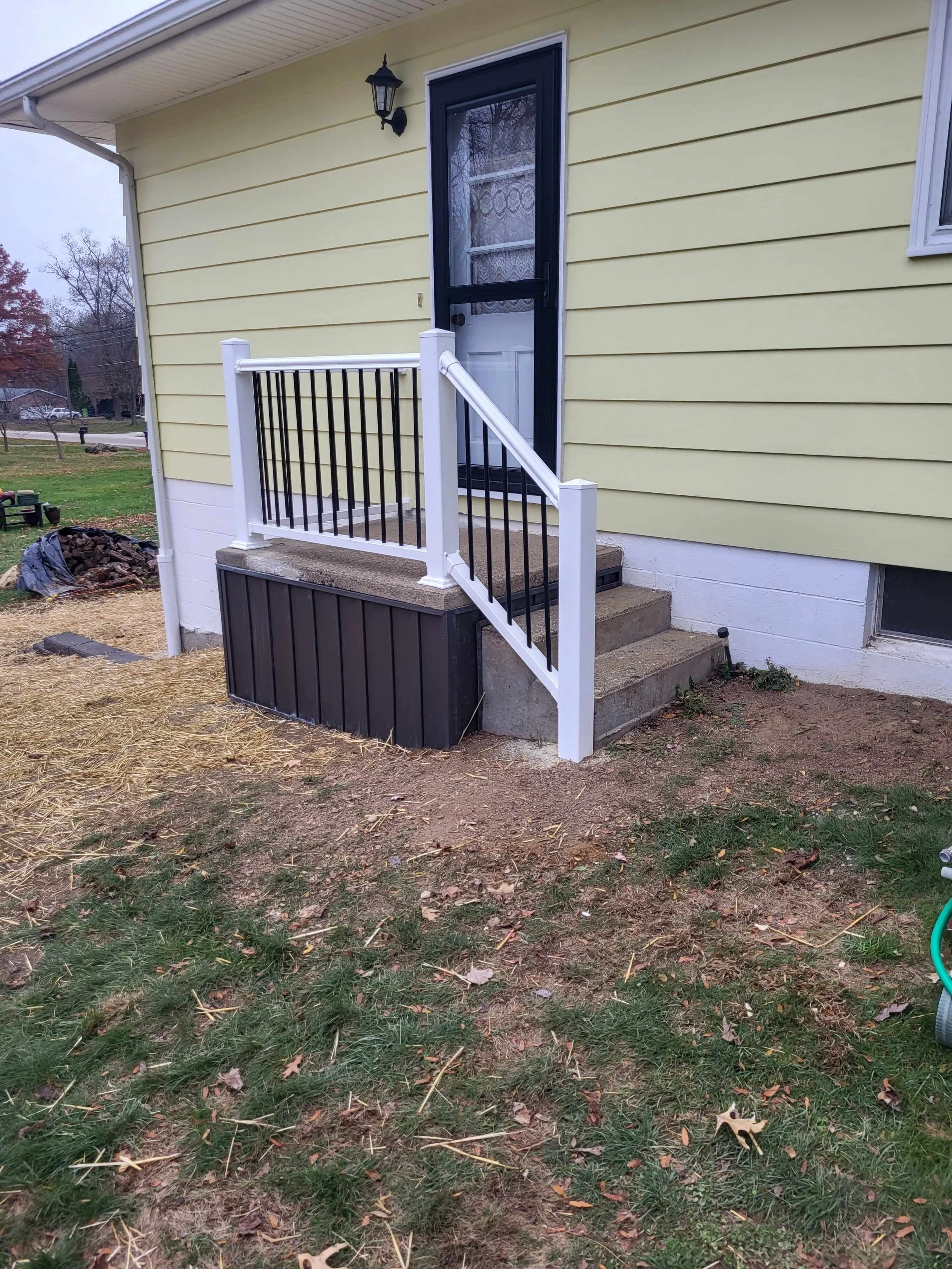 New white vinyl handrail with black aluminum spindles installed by DLR Construction on a Cuyahoga Falls porch.