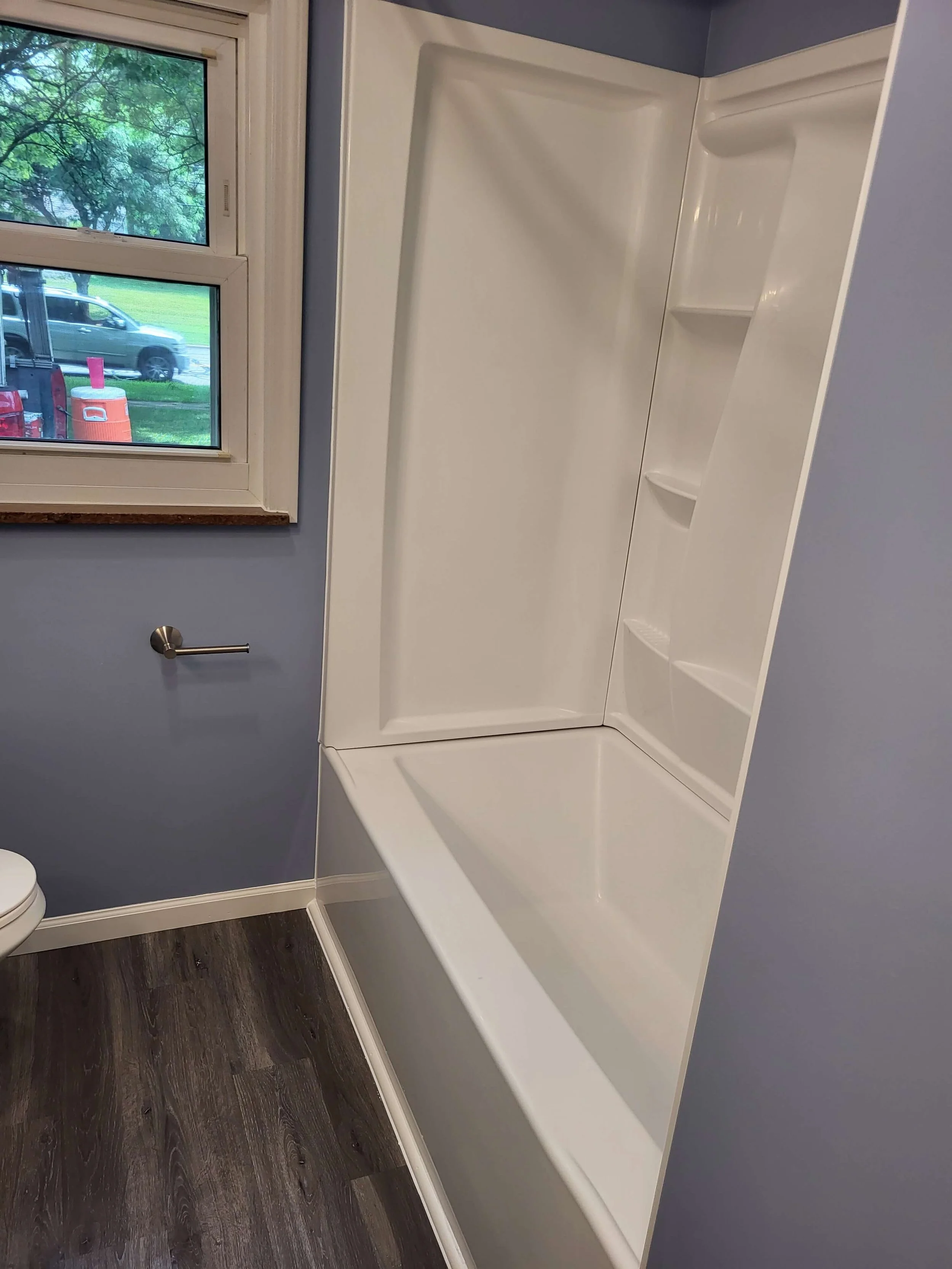 A newly installed clean white alcove bathtub and multi-shelf shower surround completed by DLR Construction in Stow Ohio.