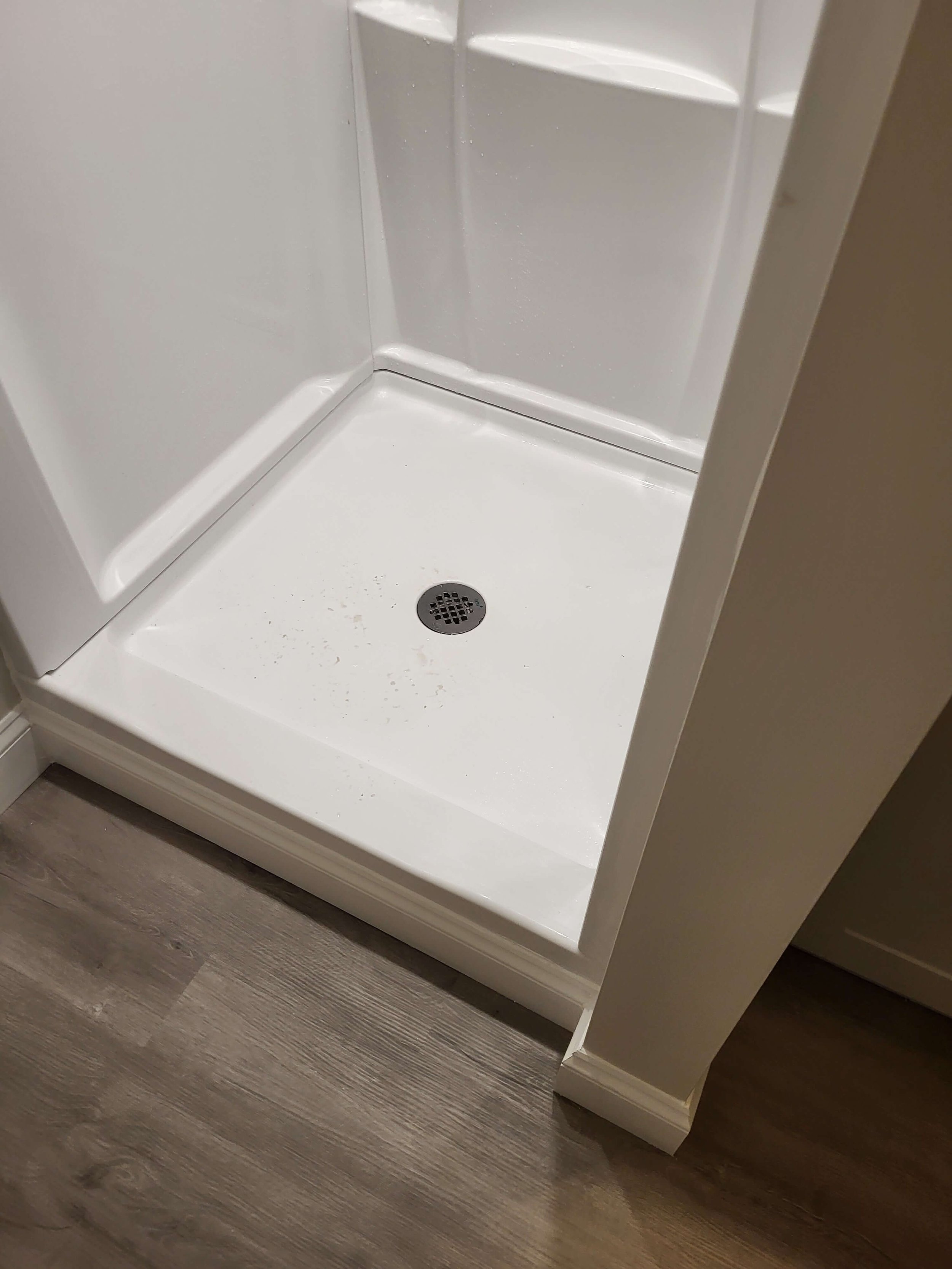 Shower base installation detail in basement bathroom