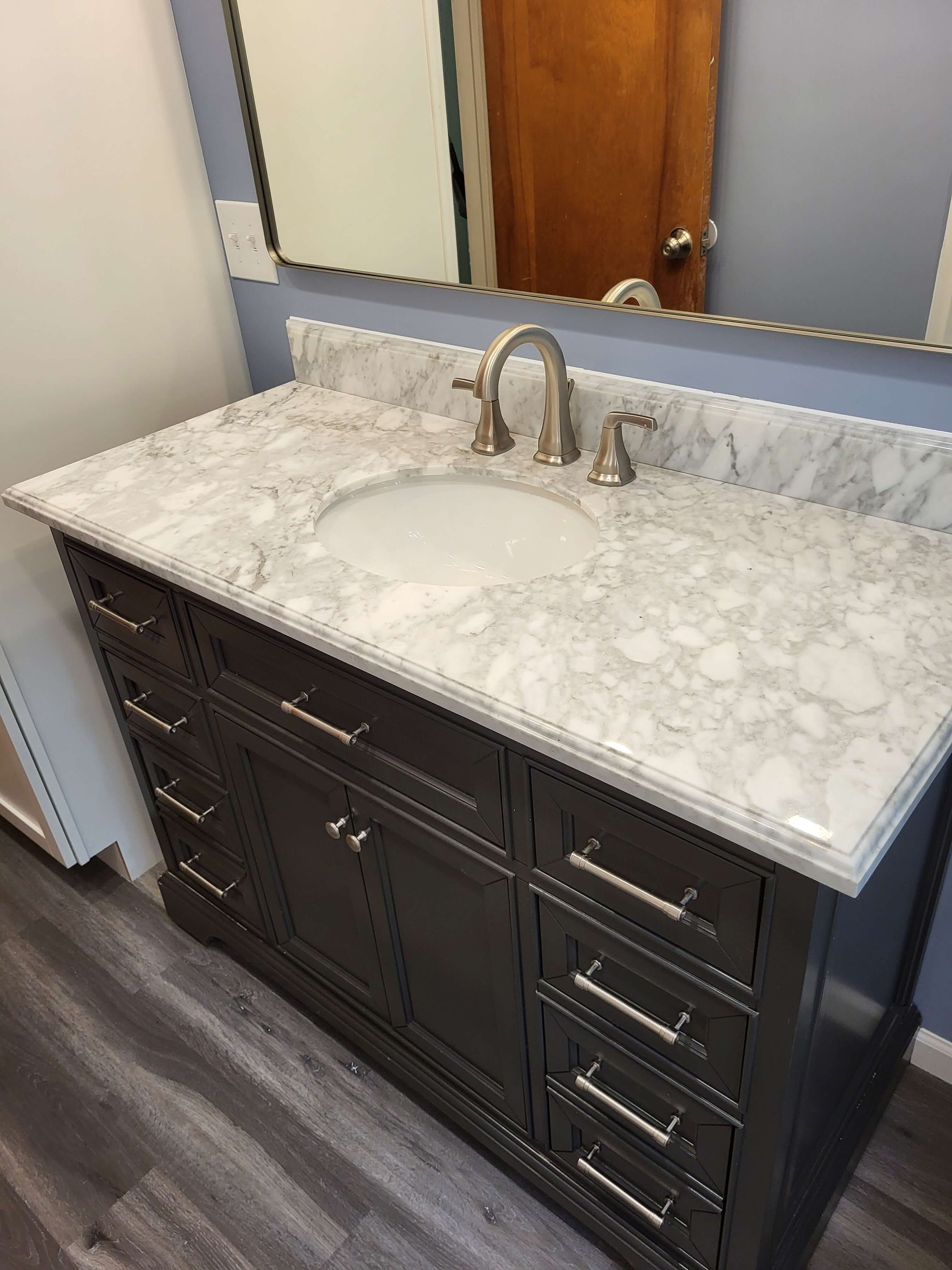 Completed Stow Ohio residential bathroom transformation featuring a new dark wood vanity matching mirror and modern lighting.