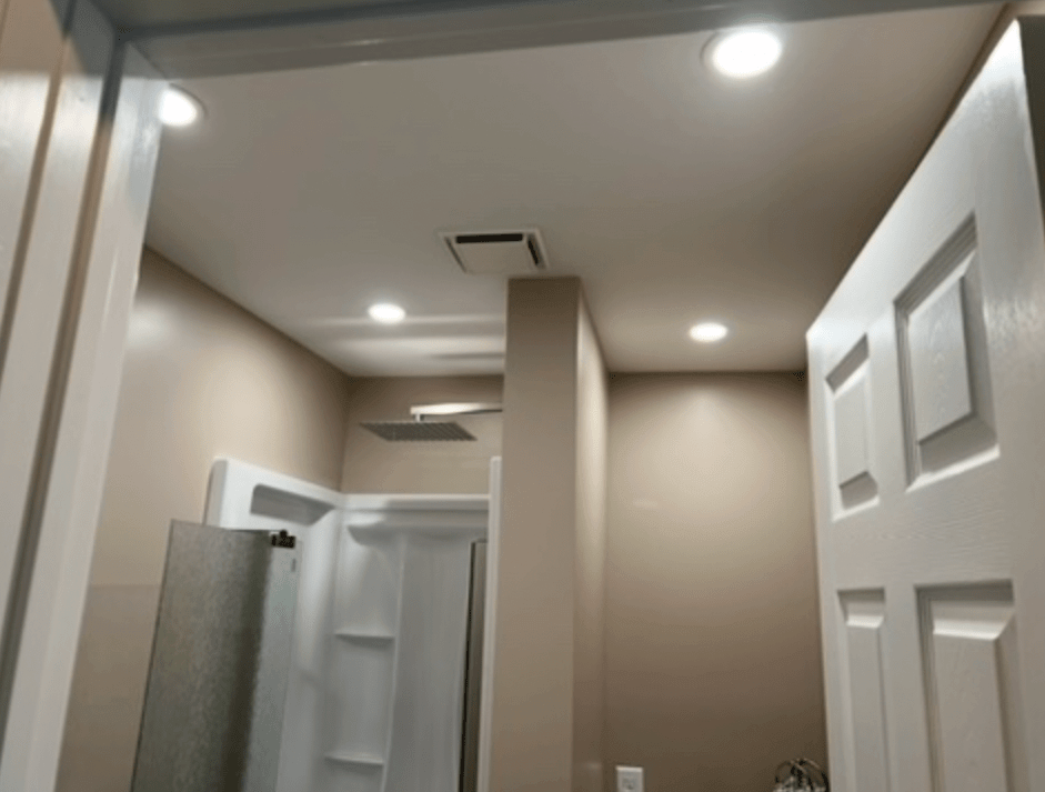 High-end basement bathroom transformation featuring a recessed ceiling-mounted waterfall shower fixture and crisp overhead lighting completed by DLR Construction in Hudson, Ohio.