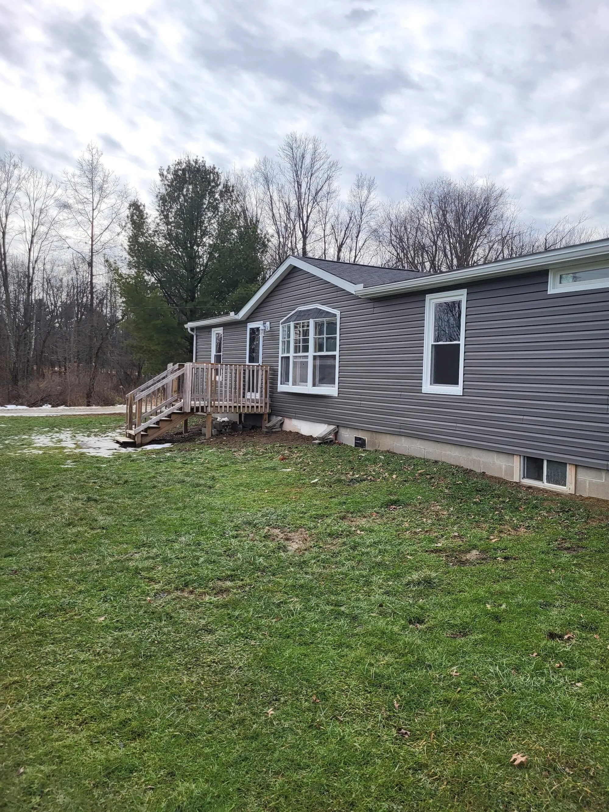 DLR Construction Completed residential exterior home remodel featuring new gray vinyl siding and white window trim in Canton, Ohio.