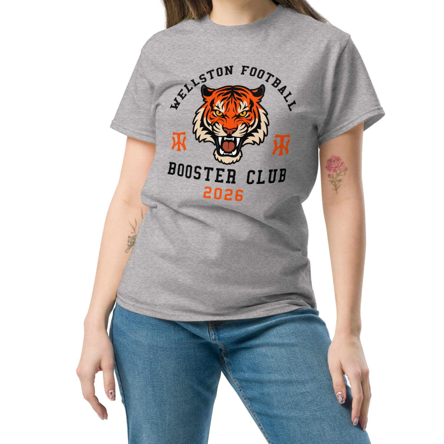Gray T-shirt with a tiger face logo, 'WELLSTON FOOTBALL BOOSTER CLUB 2026' written on it, paired with blue jeans.