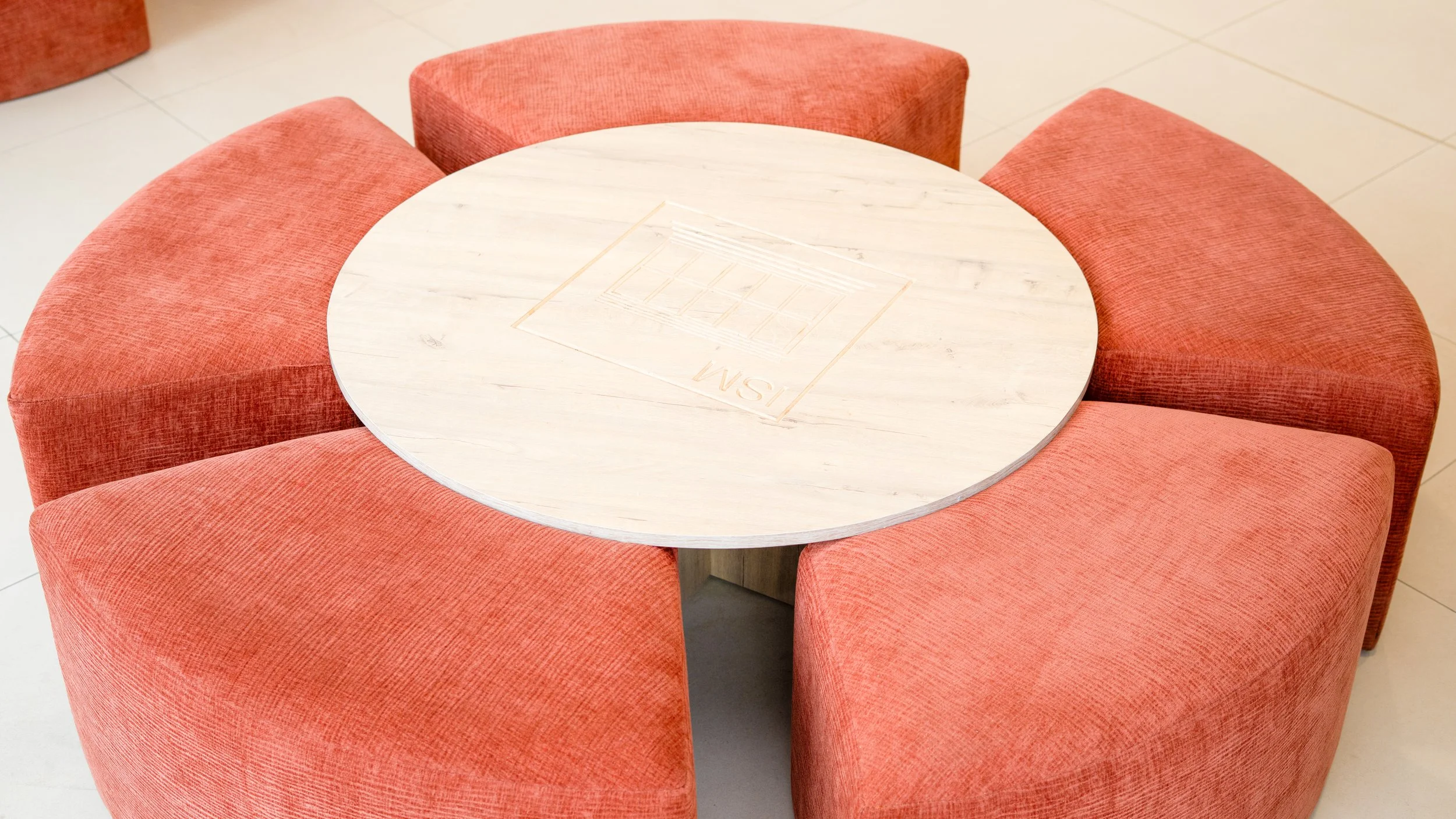Table ronde en bois clair entourée de six assises rondes en tissu orange sheznou