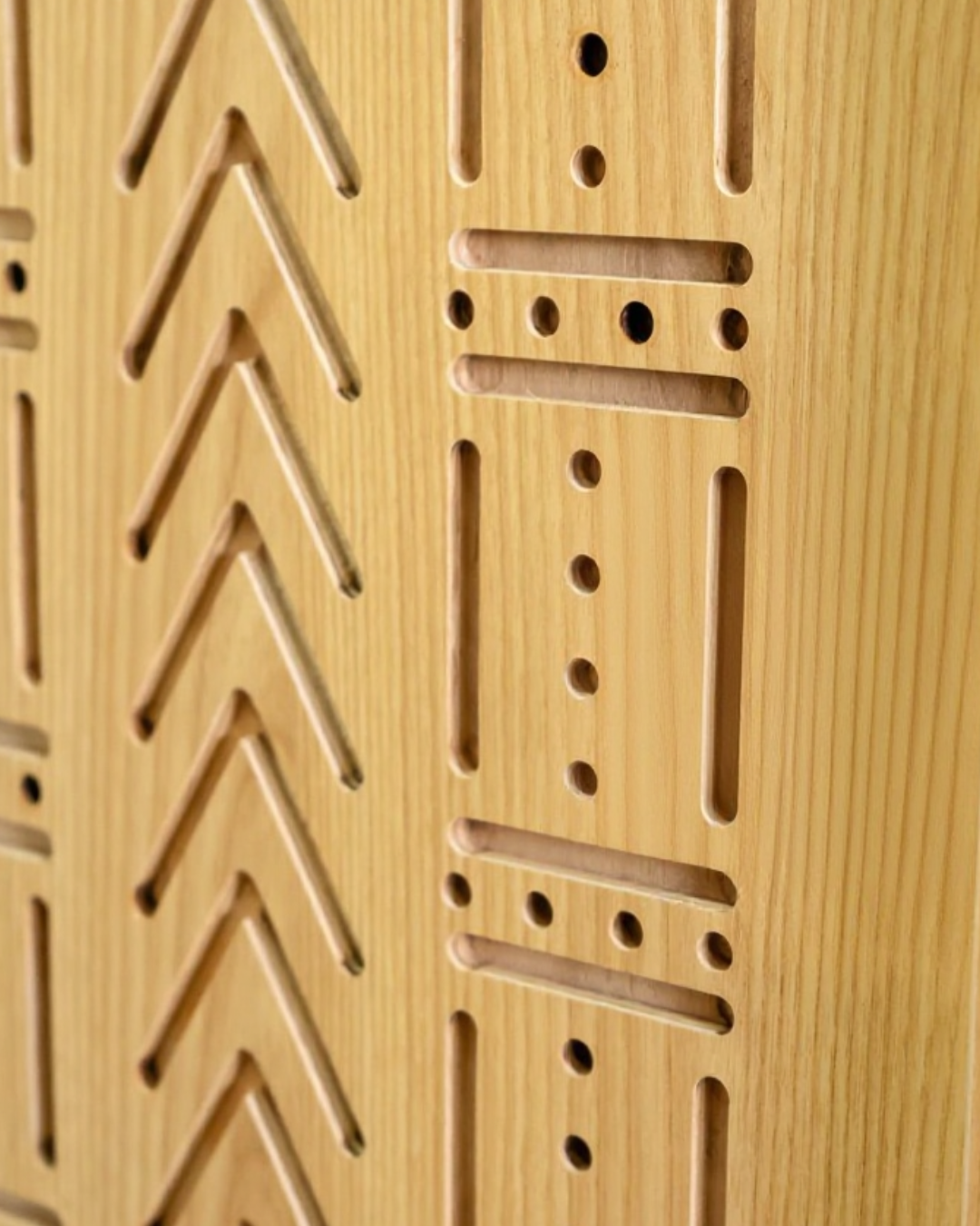 Un panneau en bois avec différentes entailles et trous, probablement pour des jeux de réflexion ou de construction. sheznou