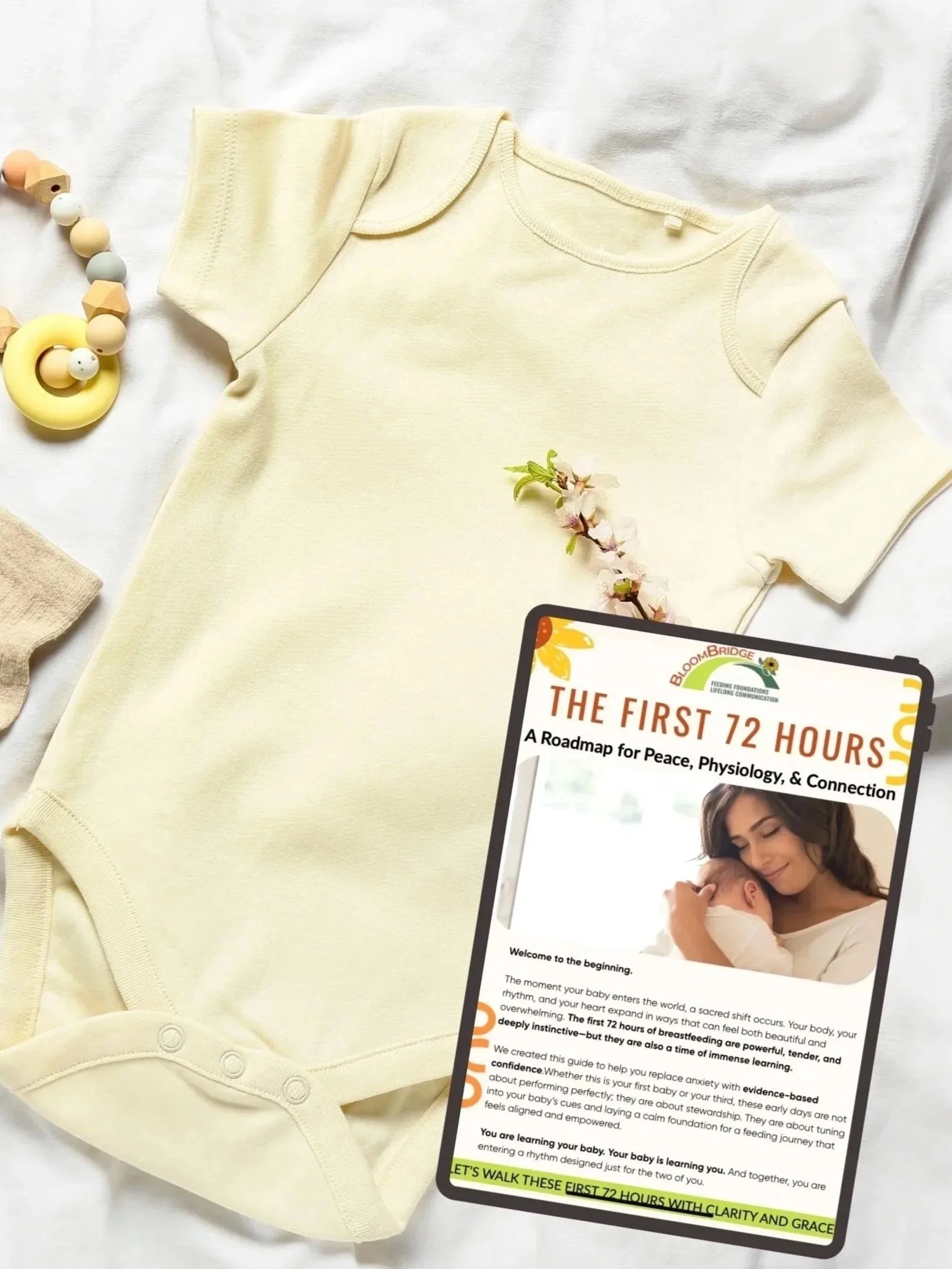 A baby onesie laid out on a white surface with a beaded pacifier toy nearby and a pink flower. A booklet titled 'The First 72 Hours' from BloomBridge Foundation with a picture of a mother holding her baby is also on the surface.