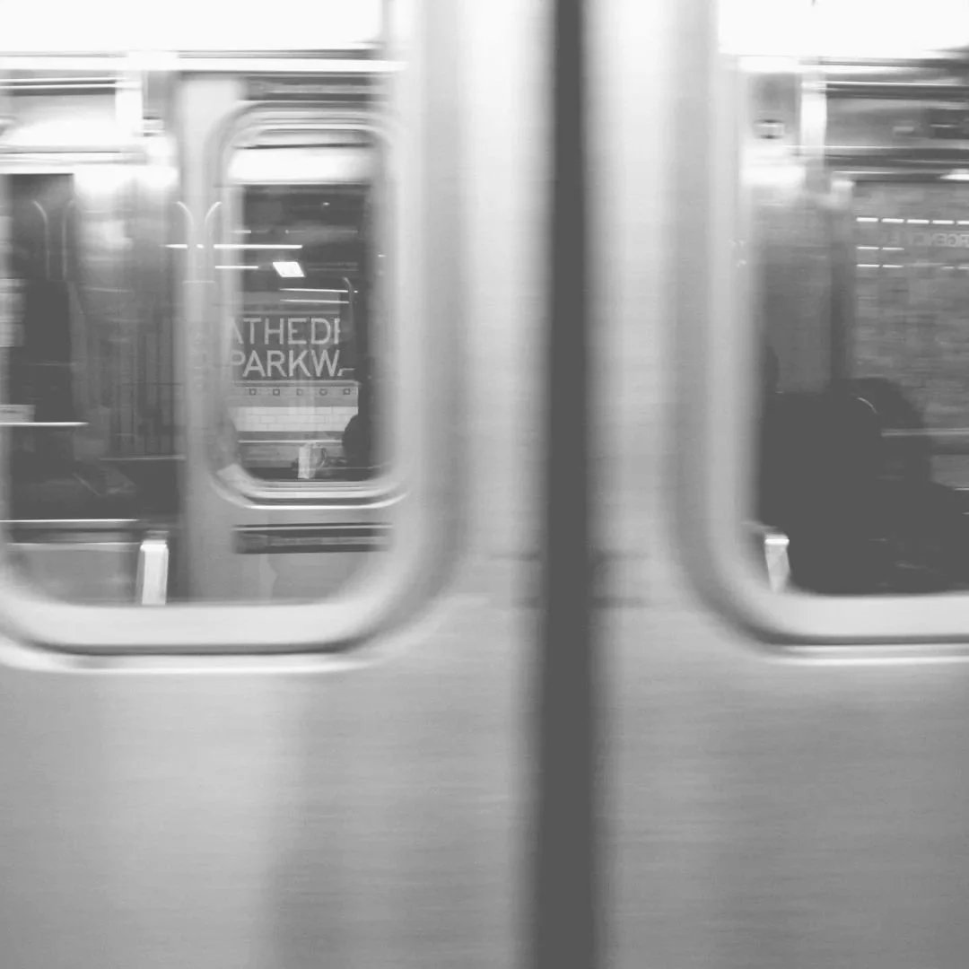 View through subway doors showing a sign for 'Athedi Parkw' with a blurry, greenish tint.