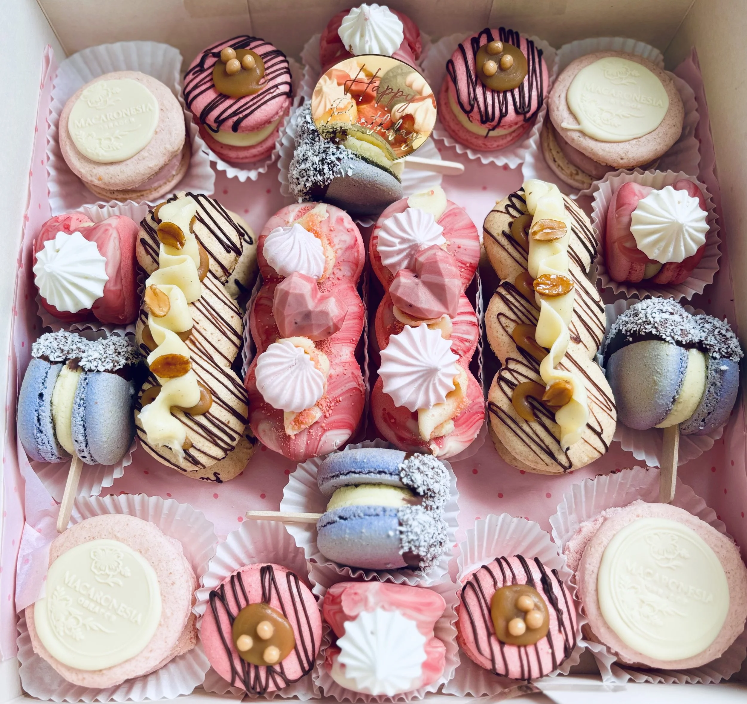 Variedad de macarons y cupcakes decorados en una caja