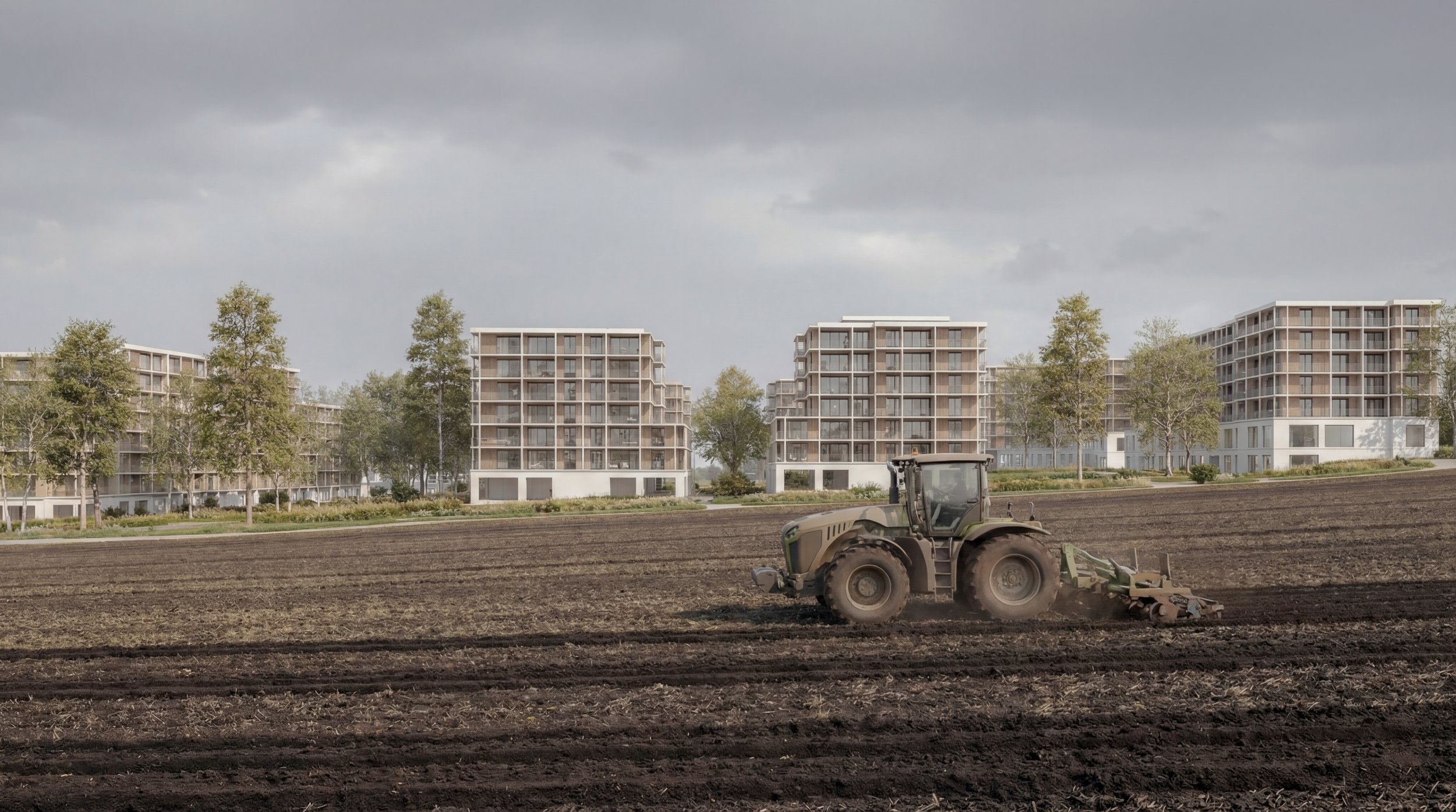 Un tracteur travaillant un champ devant des immeubles résidentiels modernes avec des arbres et un ciel nuageux en arrière-plan.