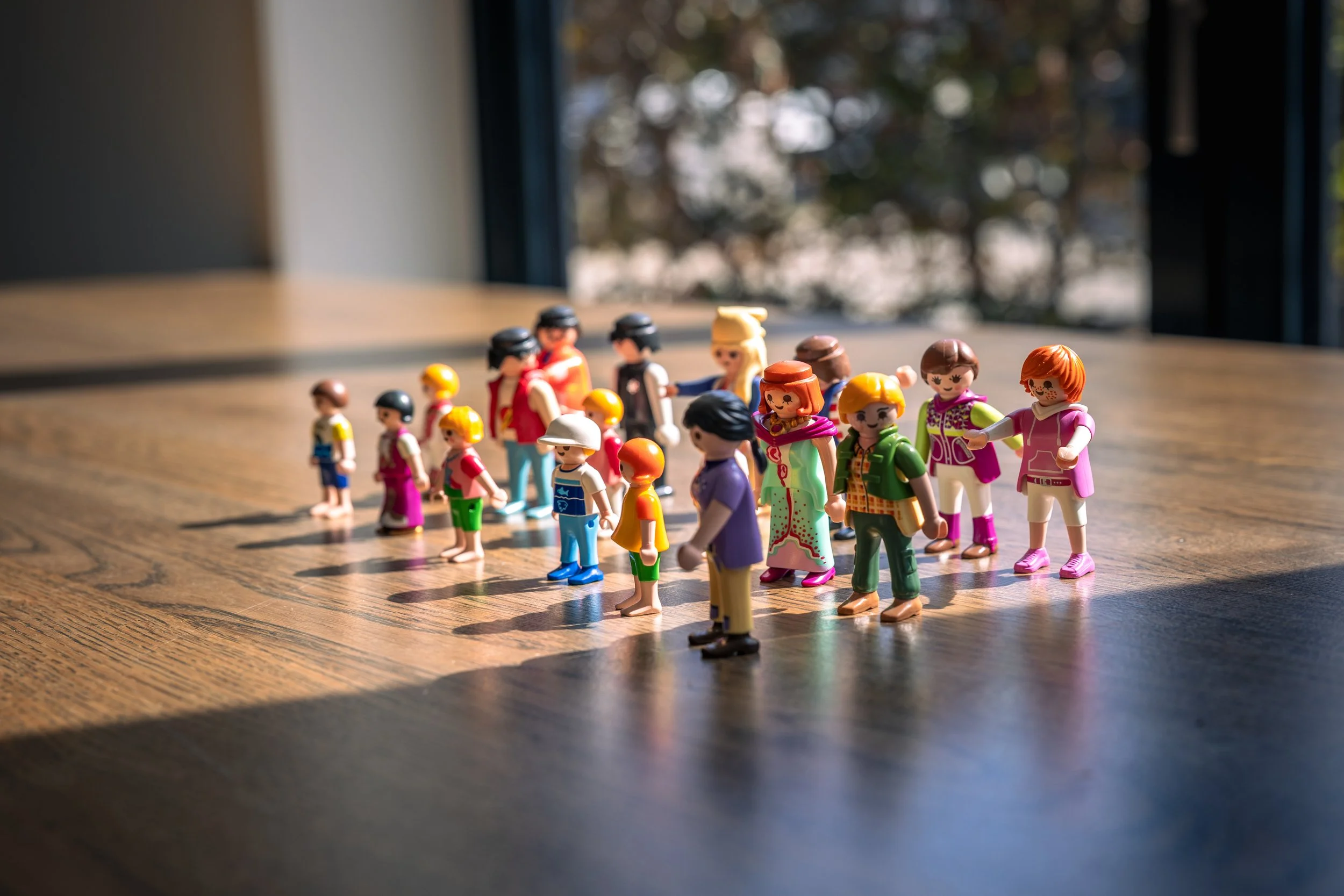 Verschillende plastic poppen op een houten tafel met natuurlijke lichtinval.