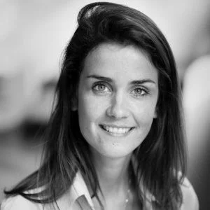 Portret van een lachende vrouw met donkere haar en lichte ogen, zwart-witfoto.