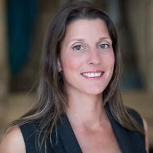 Portret van een vrouw met bruin haar, glimlachend, in een zwarte outfit.