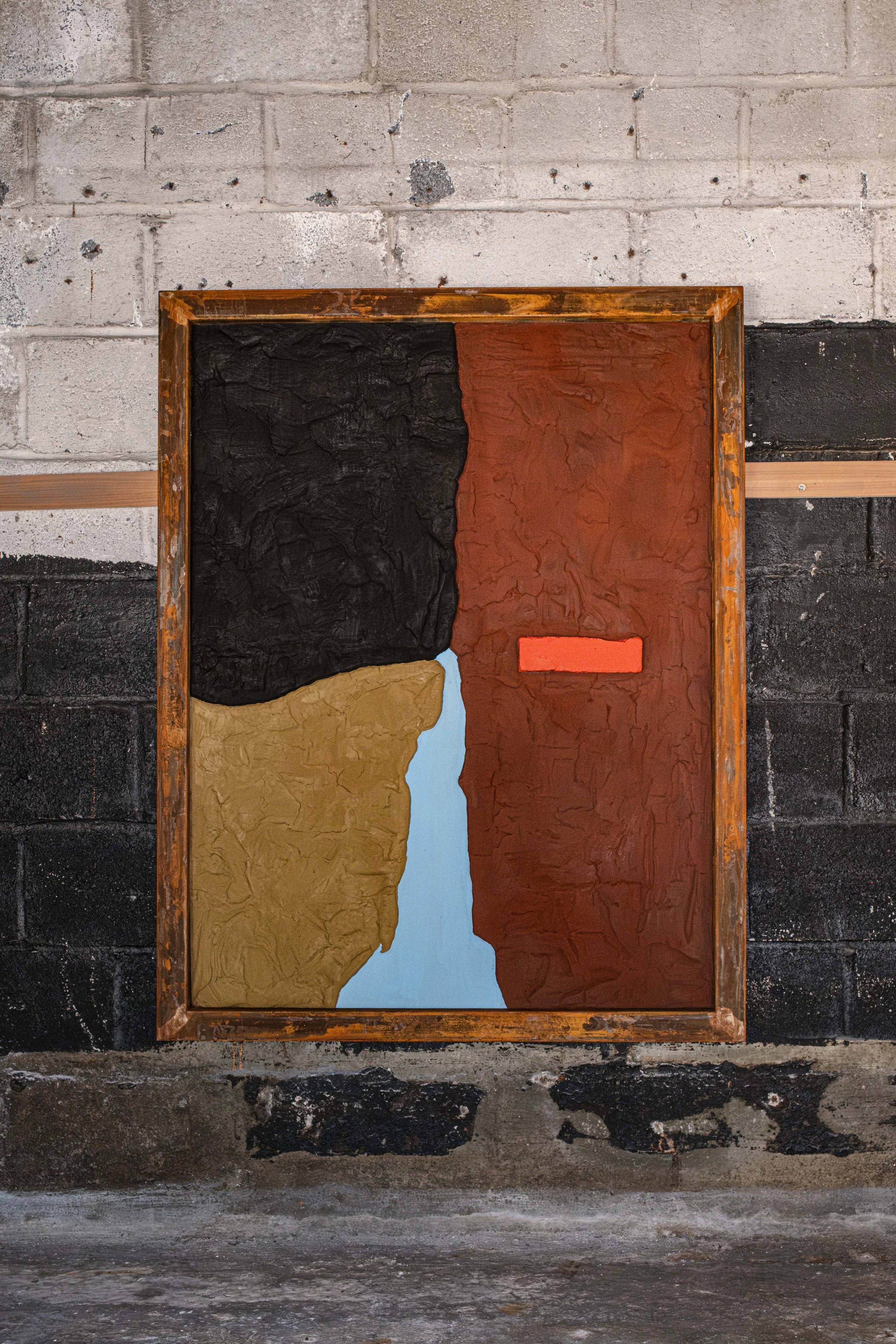 A colorfield sculpture painting hangs with a rusted steel frame around it. Black and rust and vermillion and golden tan and blue.