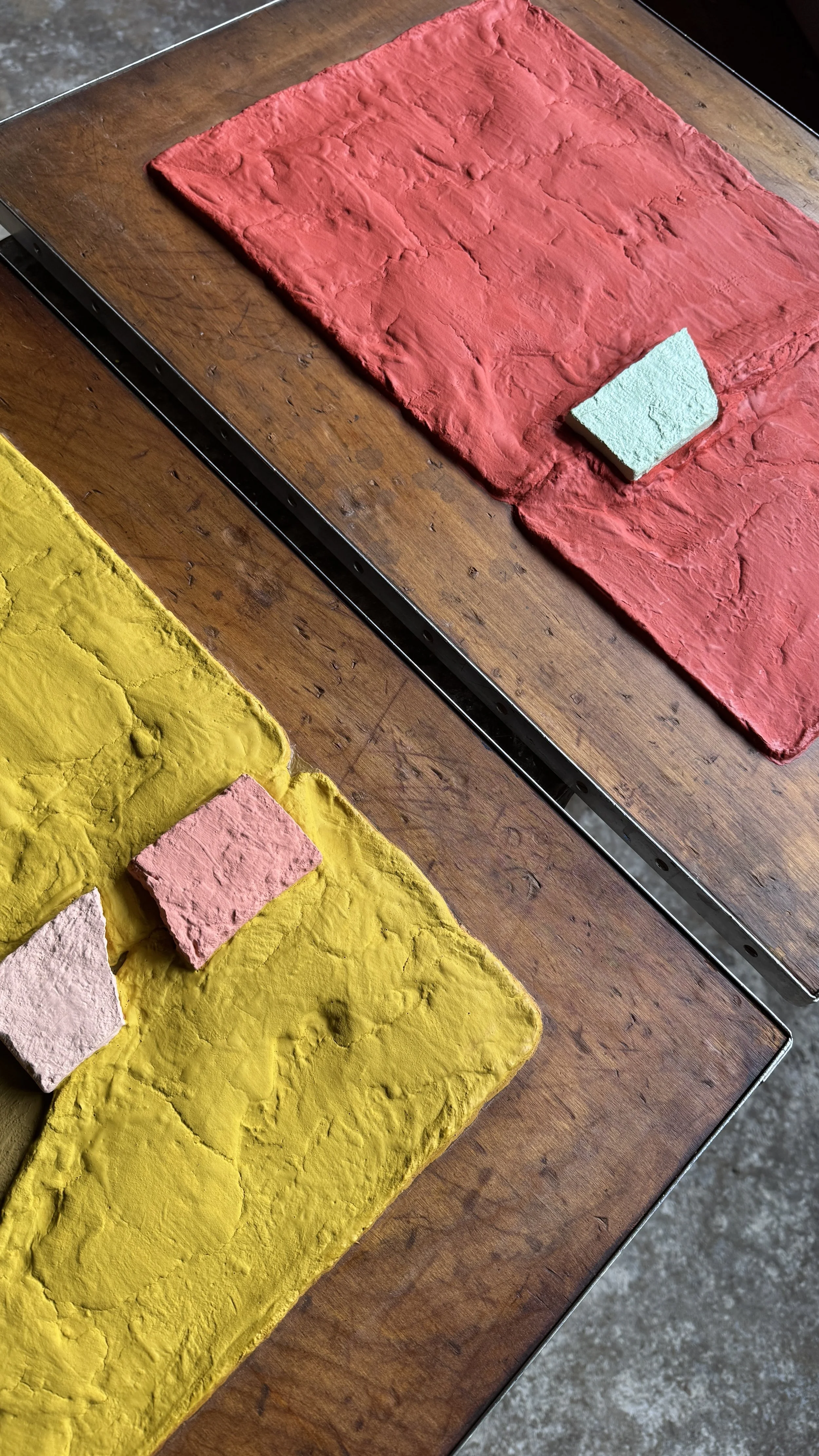 Two paintings side by side on a table, diagonal shot, showing the texture clearly. Red and yellow are each dominant color.