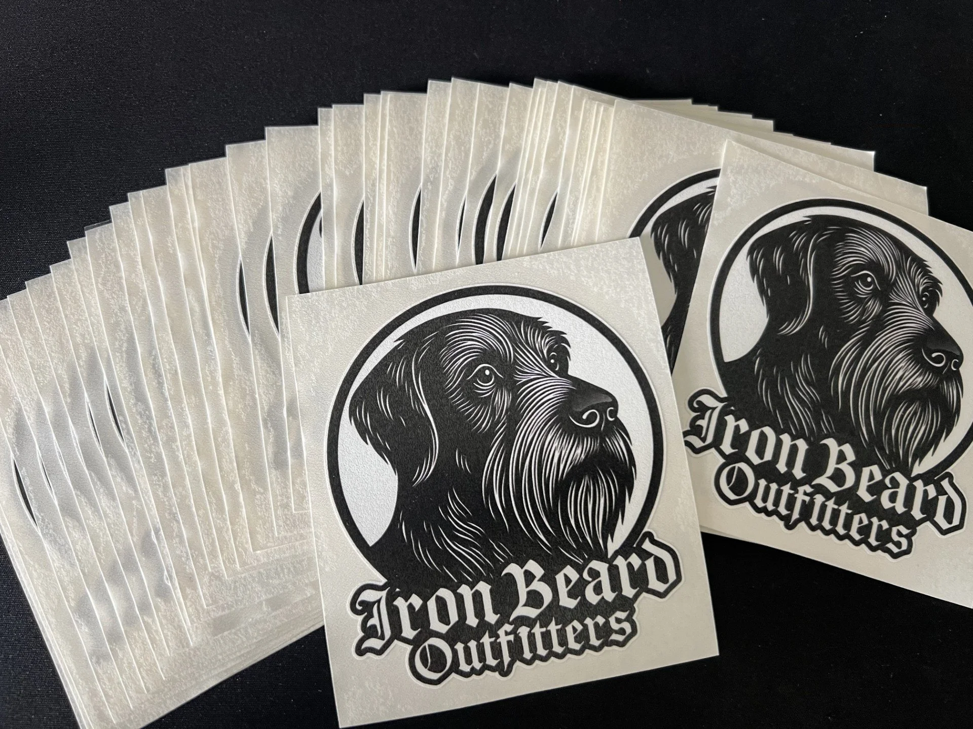 Sticker sheets with a black and white illustration of a dog's head and the text 'Iron Beard Outfitters'.
