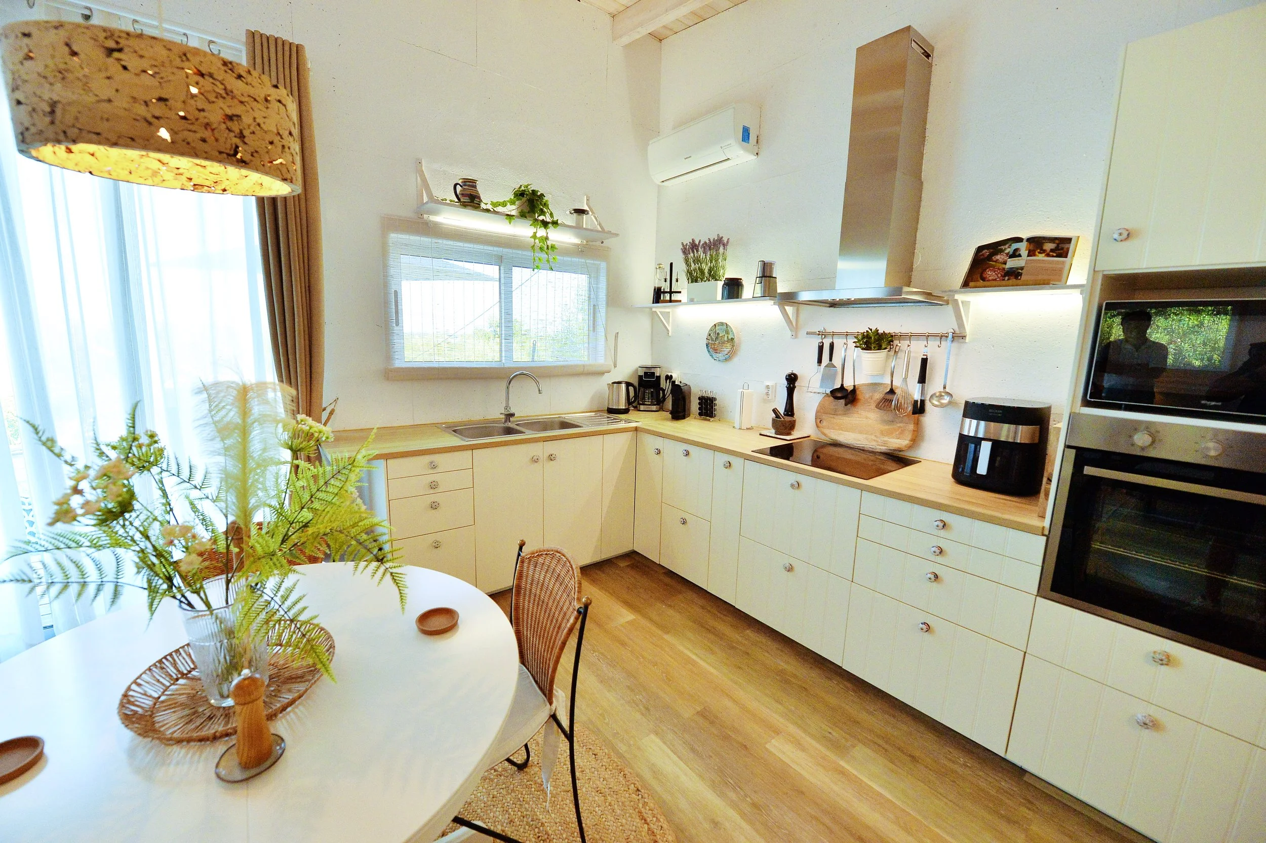 Modern kitchen with cream cabinets, wooden countertops, and a dining table with a floral centerpiece.