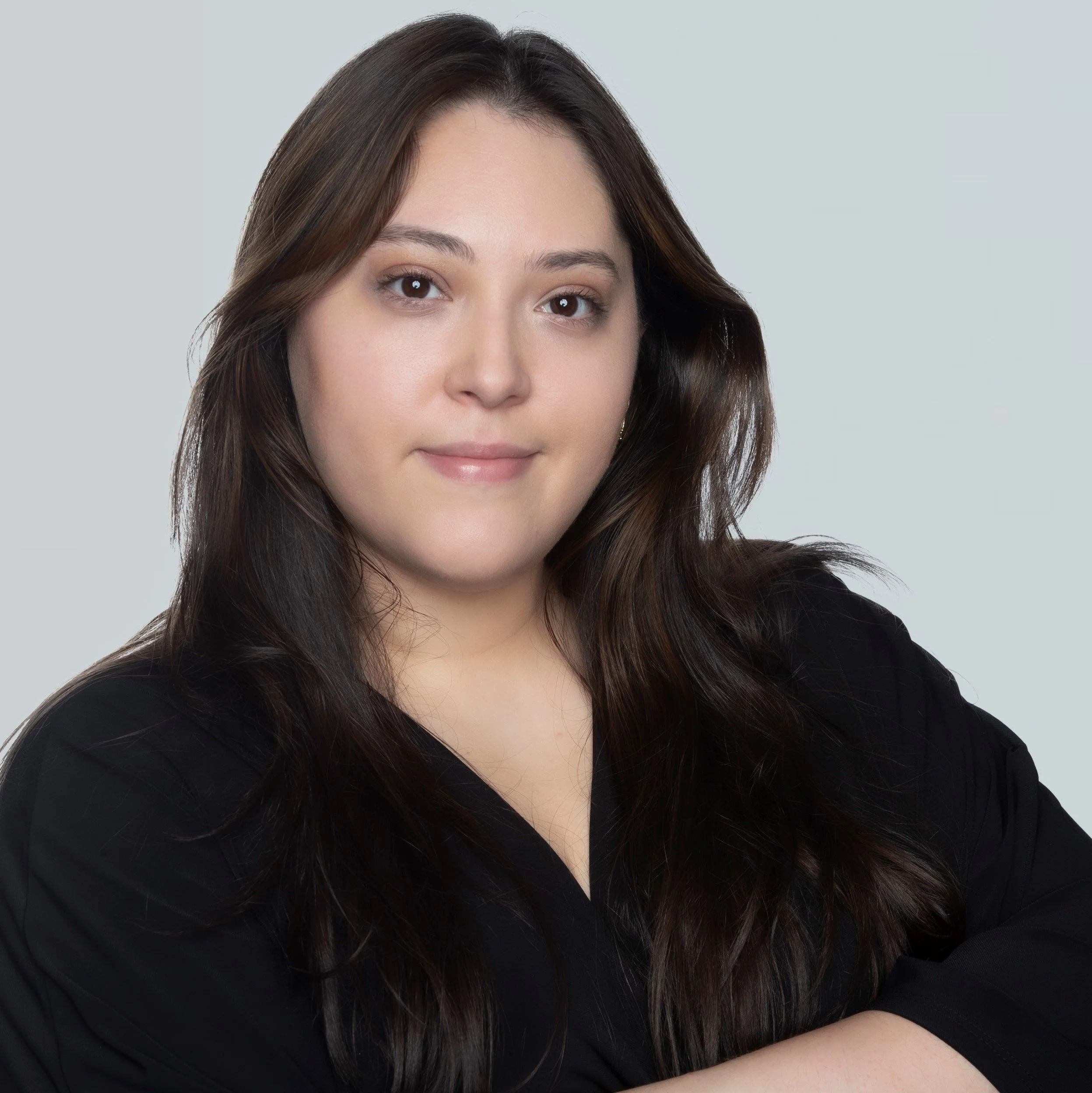 Headshot of a woman with long brown hair wearing a black top, looking directly at the camera with a neutral expression.