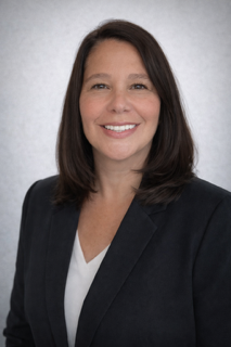 Headshot of a woman with brown hair smiling against a plain background.