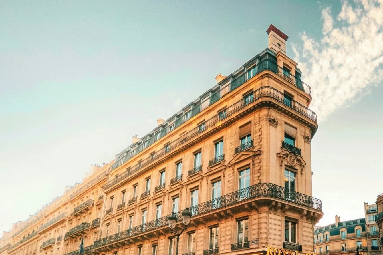 Snow-capped mountains under a cloudy sky with grassy hills in the foreground.