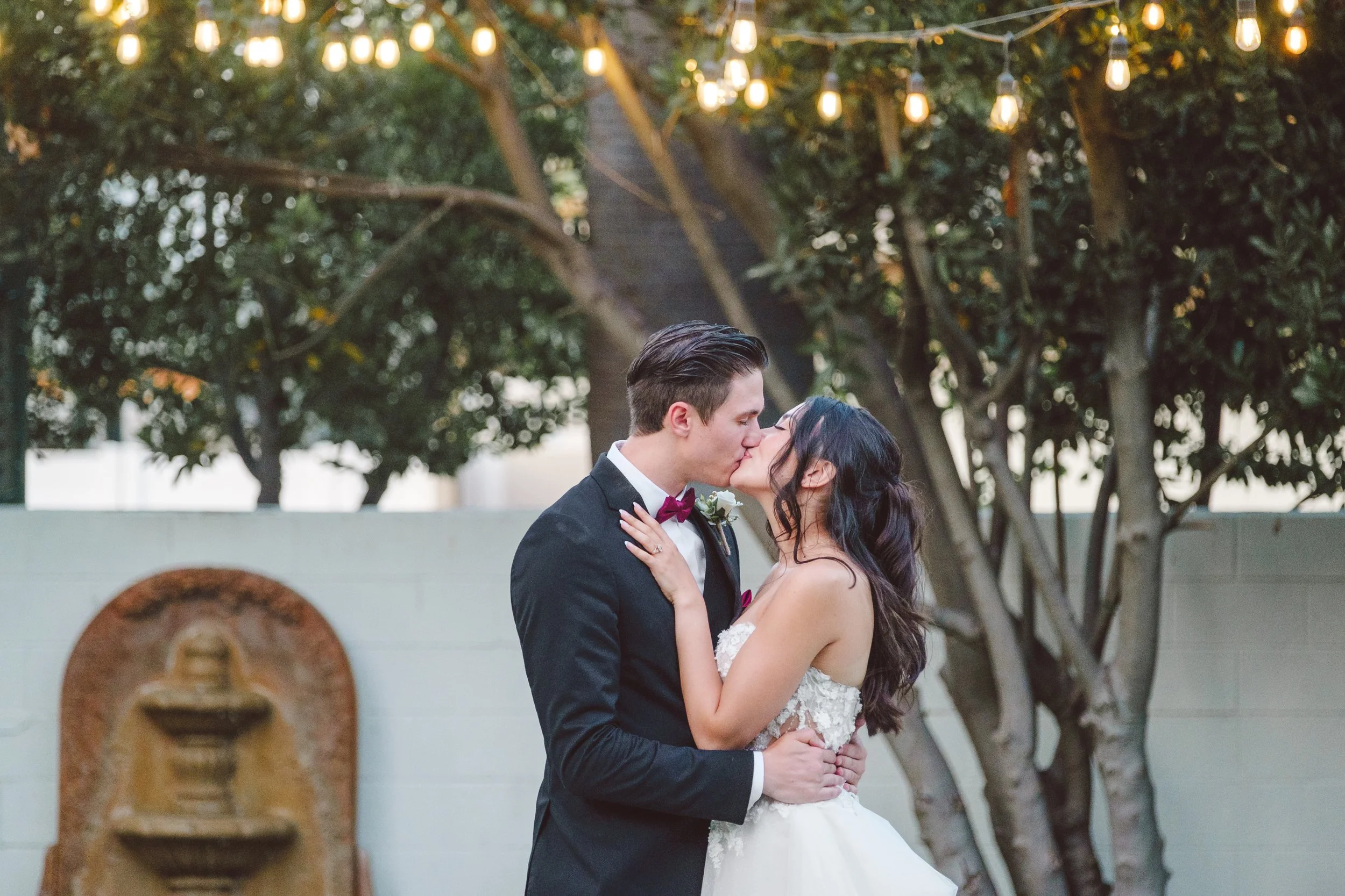 Romantic portrait of the bride and groom beneath string lights at their Los Serranos Country Club wedding reception in Chino Hills CA.