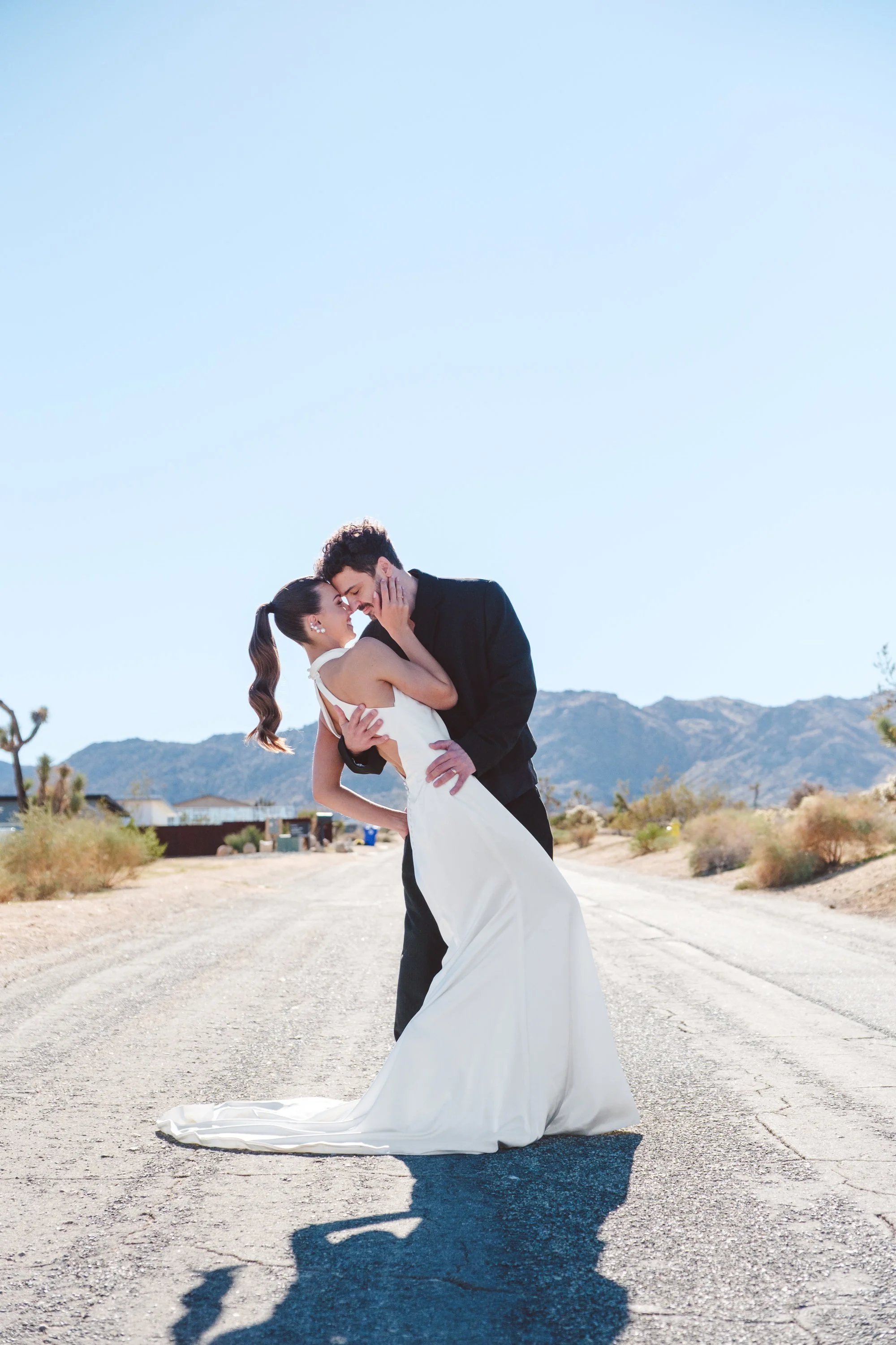 Bride and groom sharing a dip kiss in the open desert landscape of Joshua Tree during an editorial styled shoot.