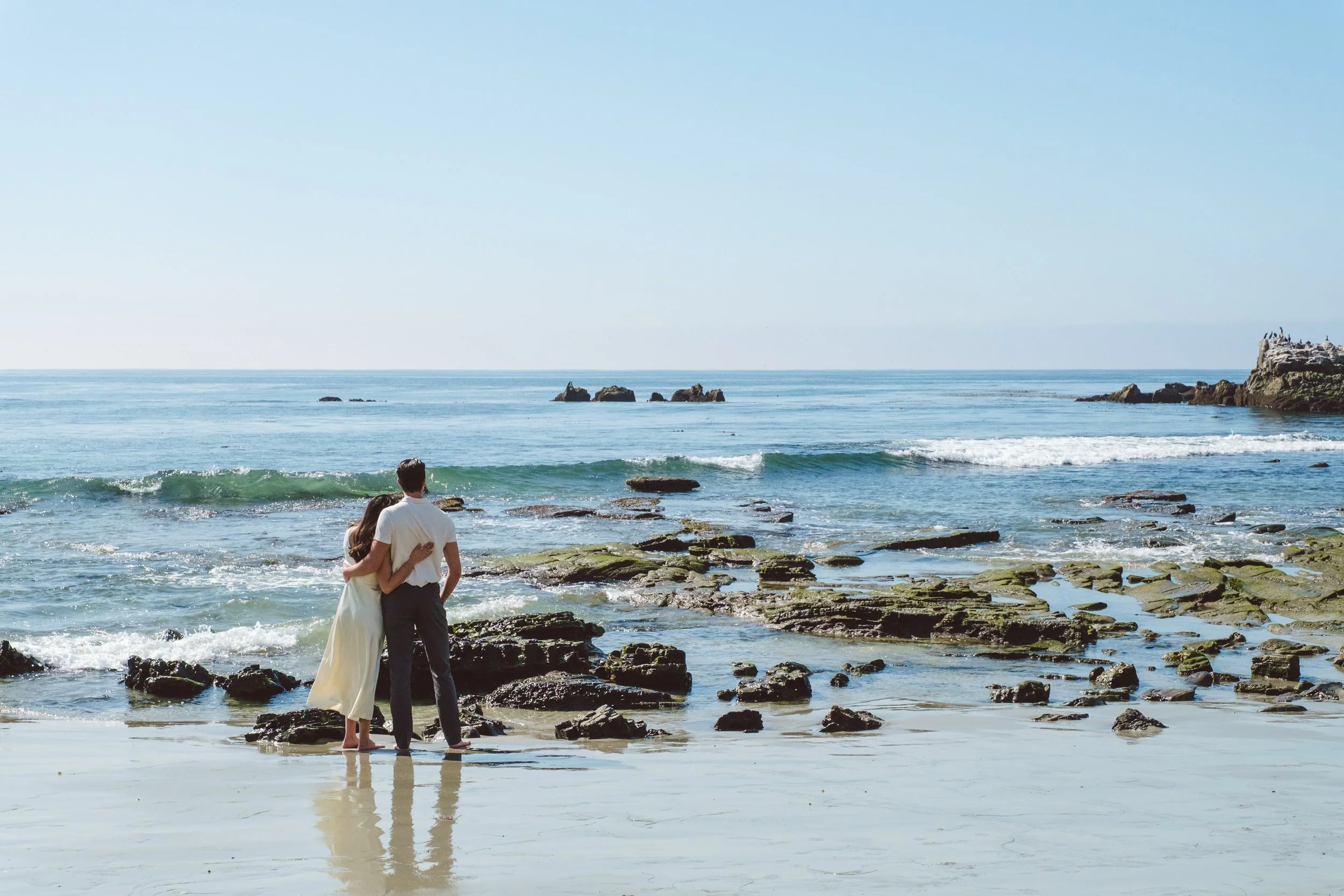 Couple walking together along the shoreline during a Laguna Beach engagement session.