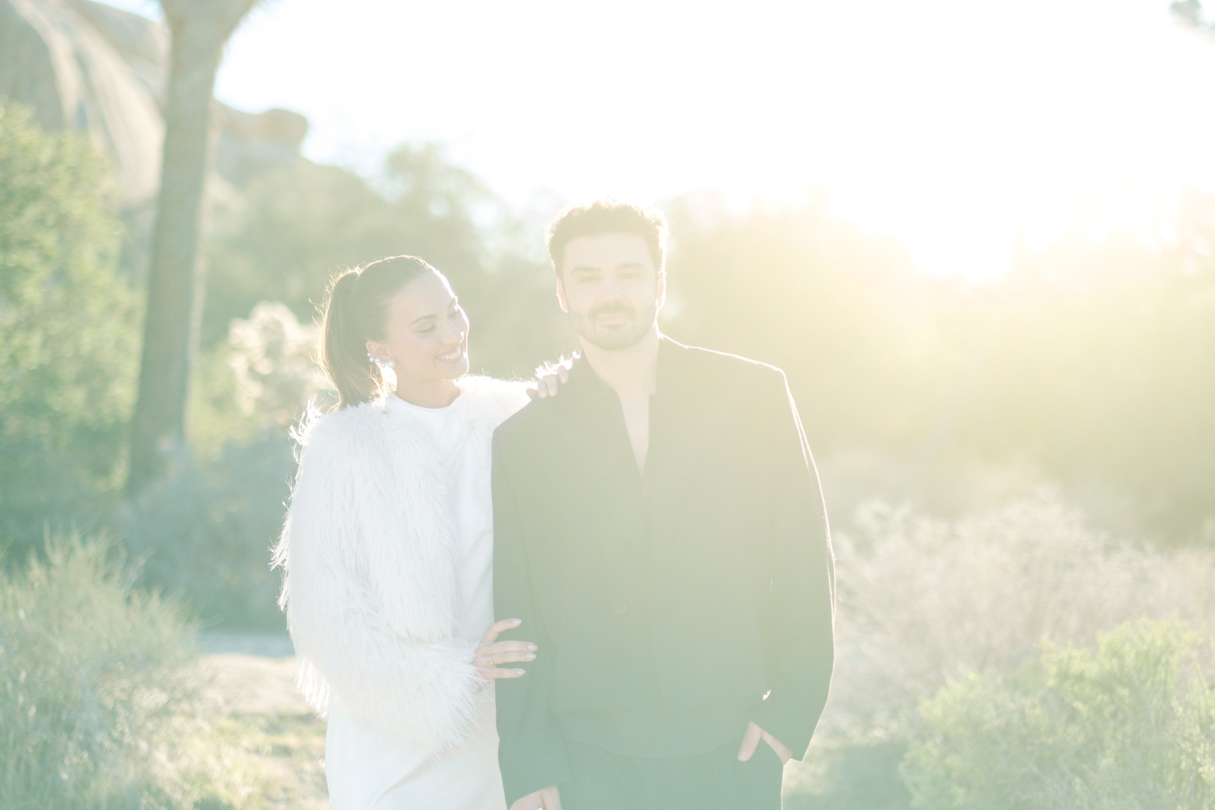 Couple standing together in the desert with sun flare and minimal styling during a Joshua Tree editorial wedding shoot.