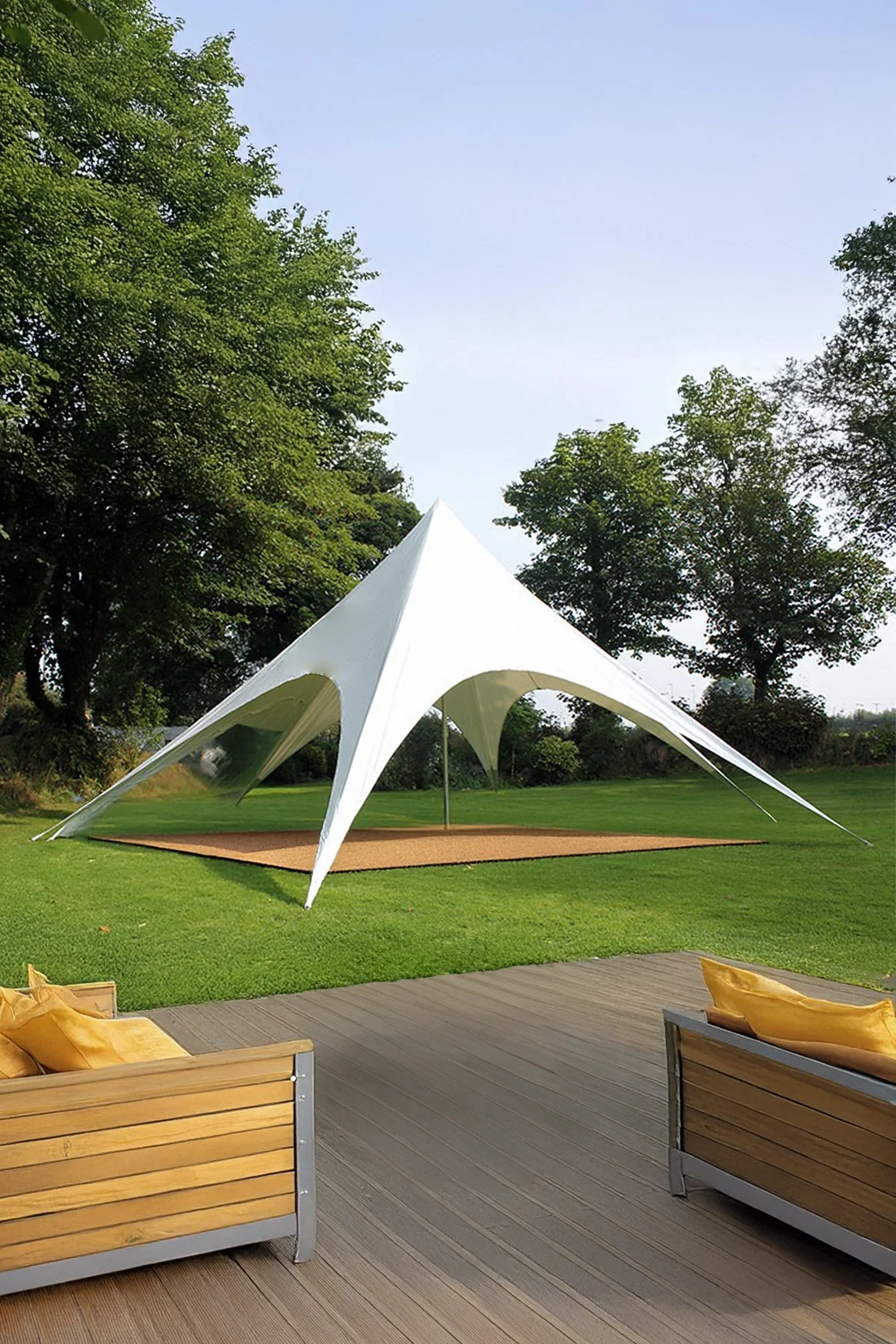 A modern white outdoor tent with a unique, futuristic design, set up on a grassy lawn with trees in the background and wooden seating with yellow cushions in the foreground.