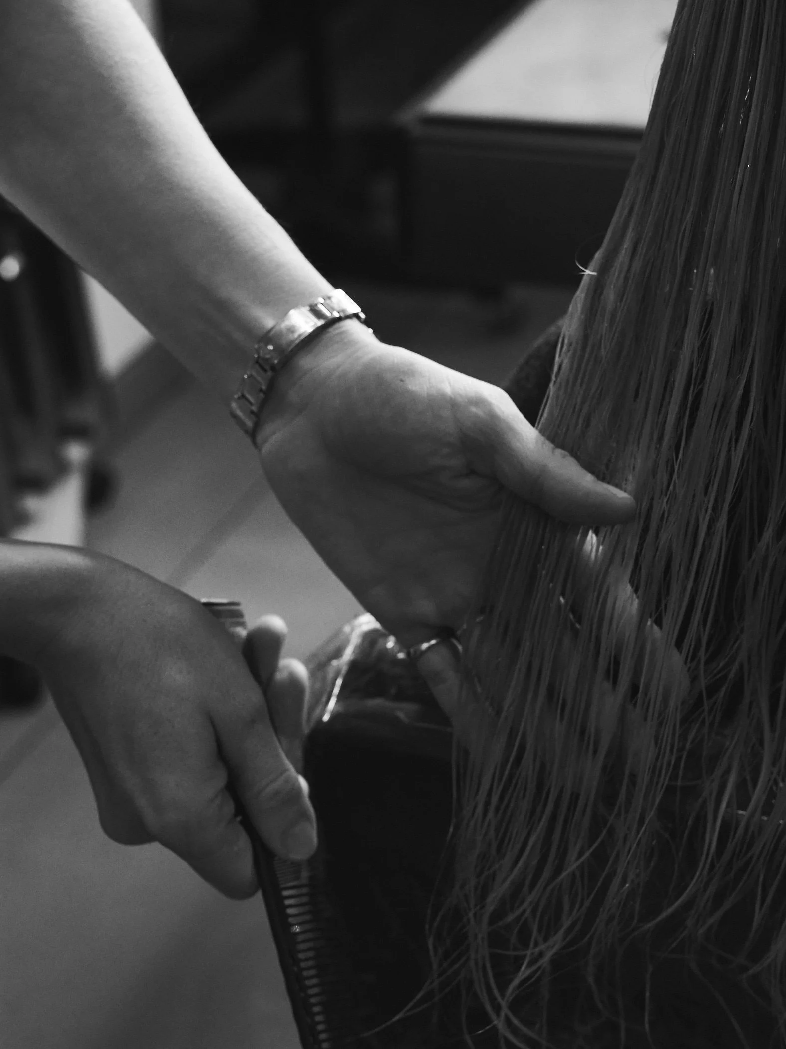 Close-up of a person cutting hair with scissors at a salon.