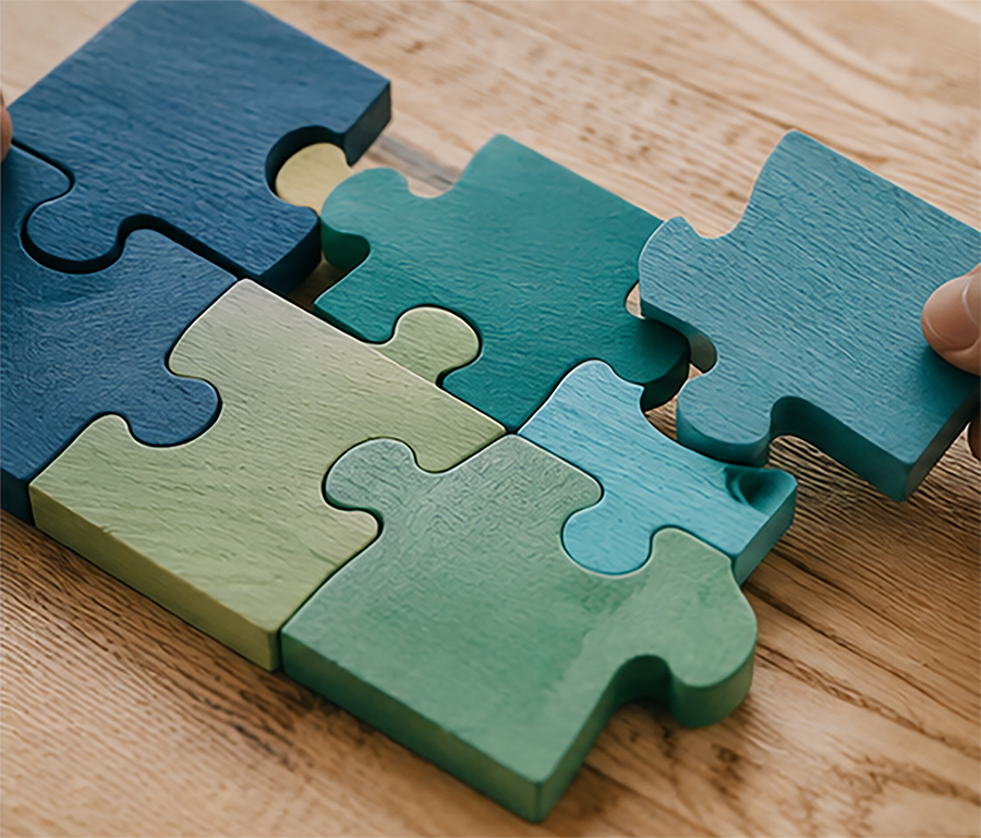 Puzzle pieces being fitted together on a wooden surface, representing collaboration and teamwork.