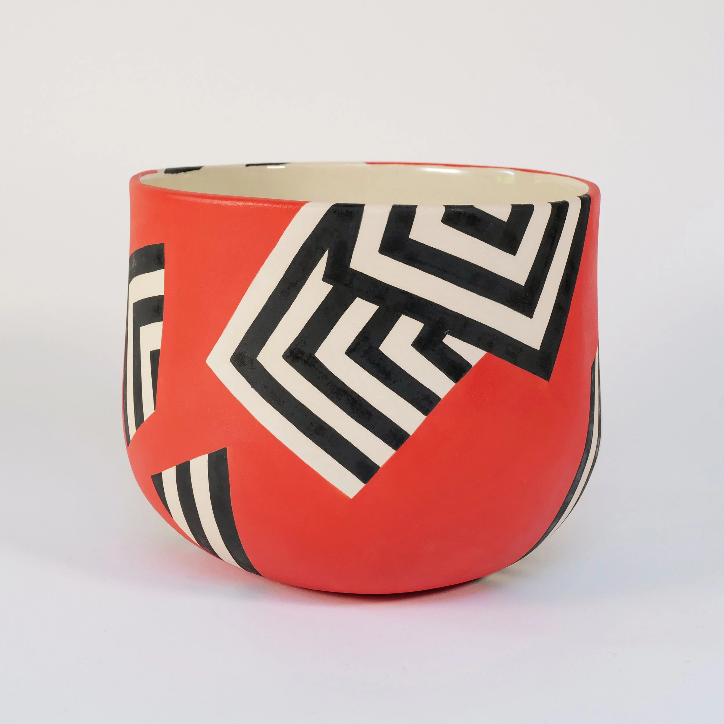 A ceramic planter with a red background and black and white geometric patterns.
