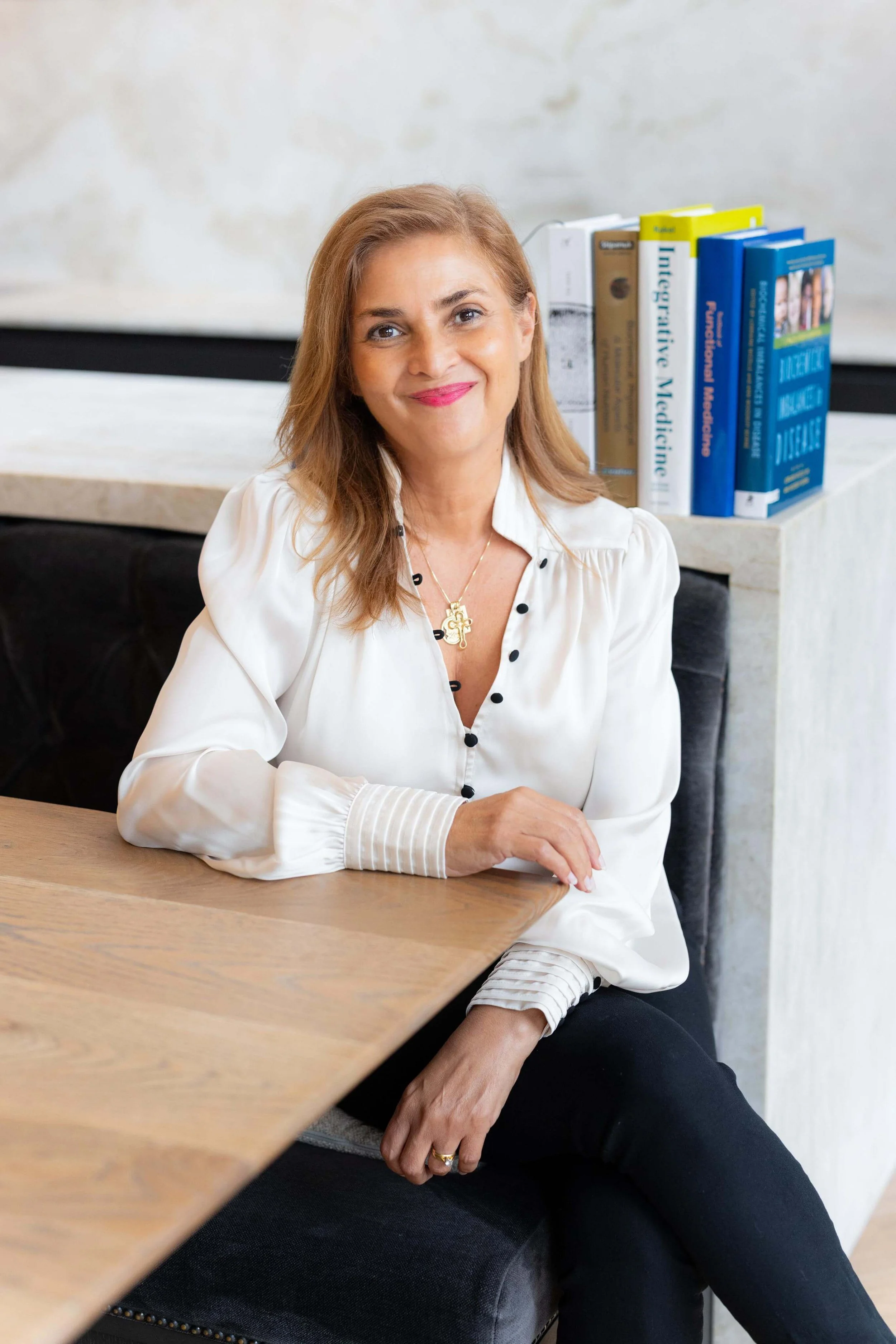 Stella smiling at the camera, wearing a cream blouse and black trousers