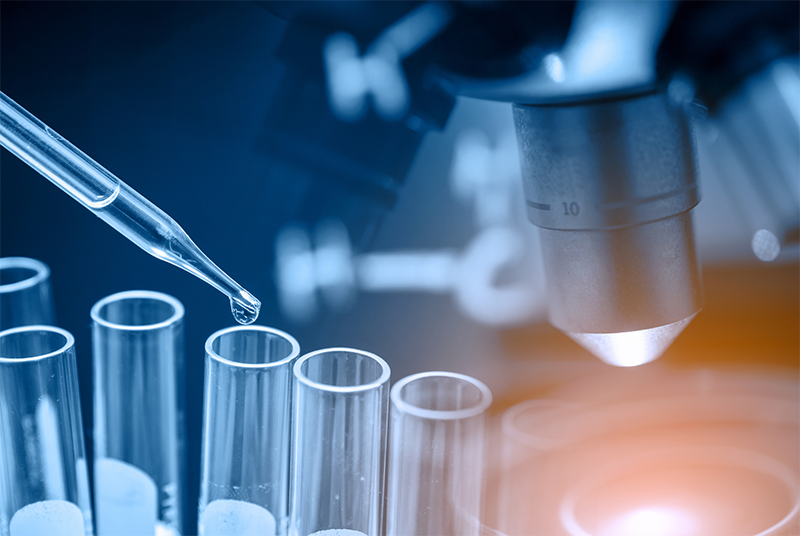 A lab setting with test tubes, a pipette dropper, and a microscope.
