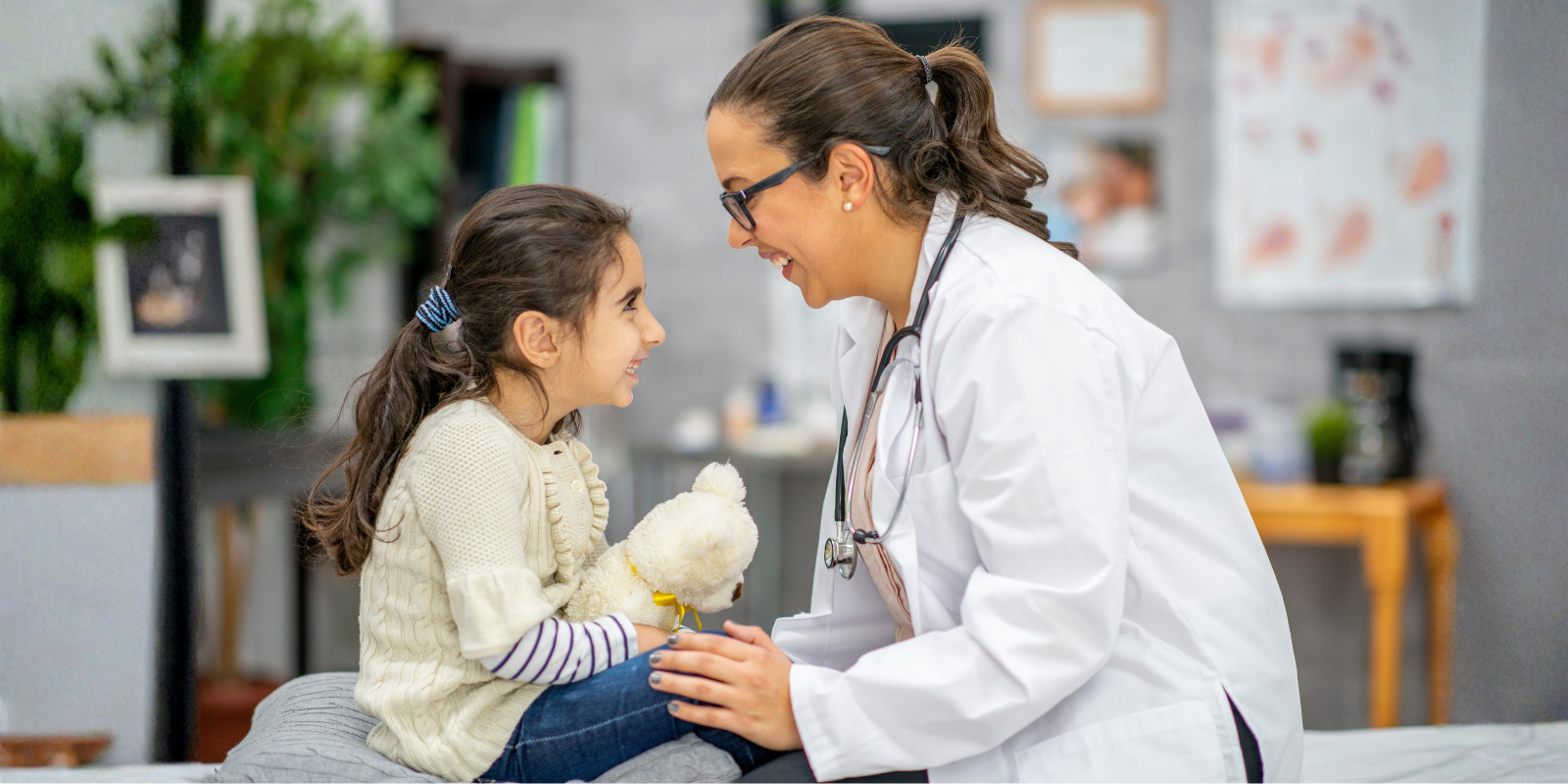 A female doctor and child, both smiling while looking at each other.