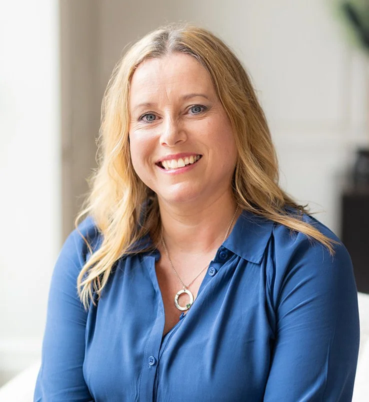 Sarah Webb, BSc, DipNT, mBANmaT, regCNHC, a won with blonde hair and blue eyes wearing a blue blouse and a silver necklace.