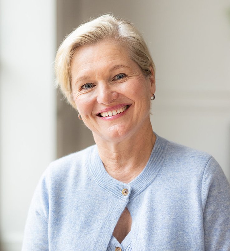 Emma Mace, nutritional therapist, smiling with short blonde hair, wearing a light blue button-up cardigan.