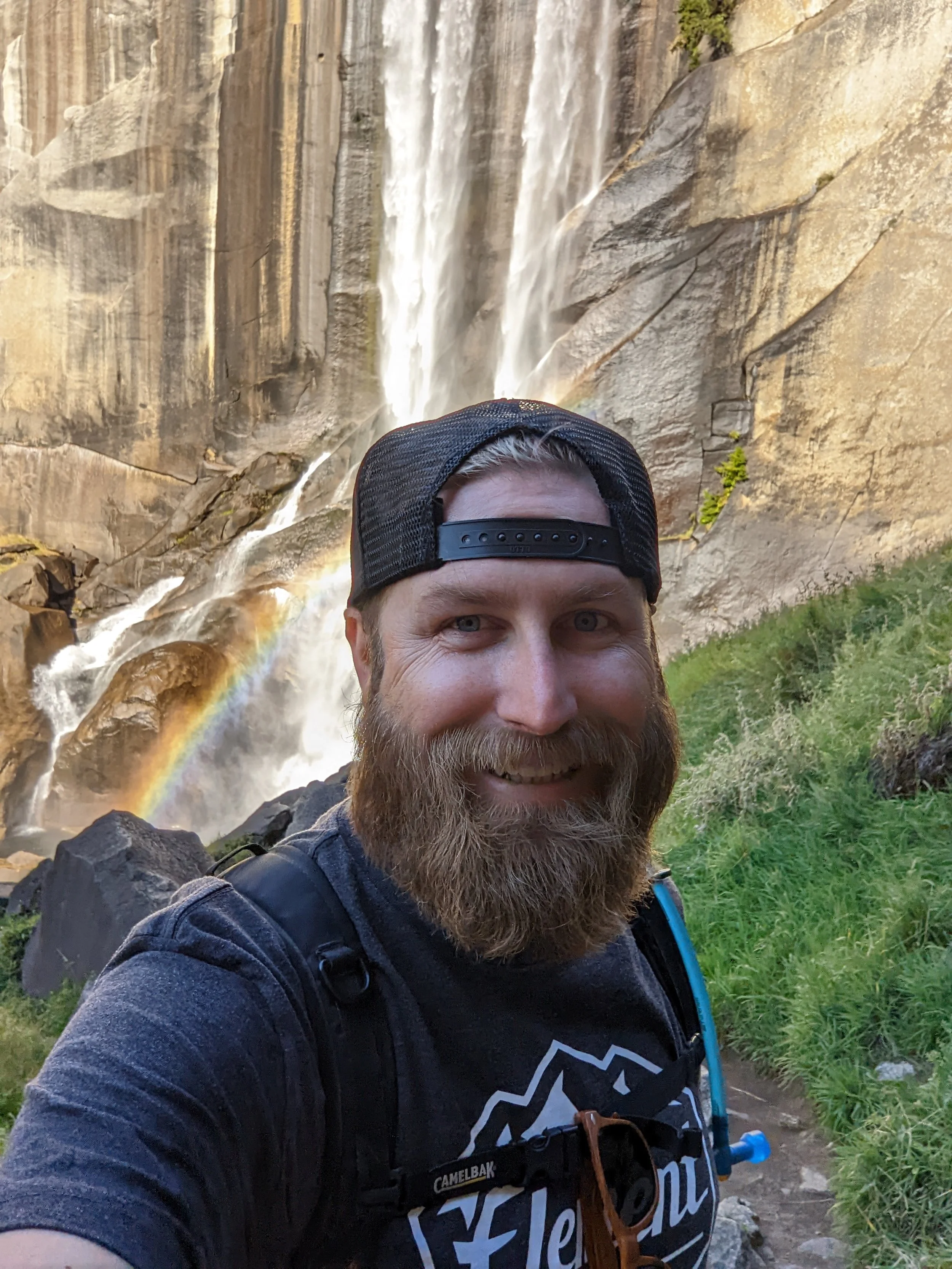 Man standing infront of a waterfall smiling 