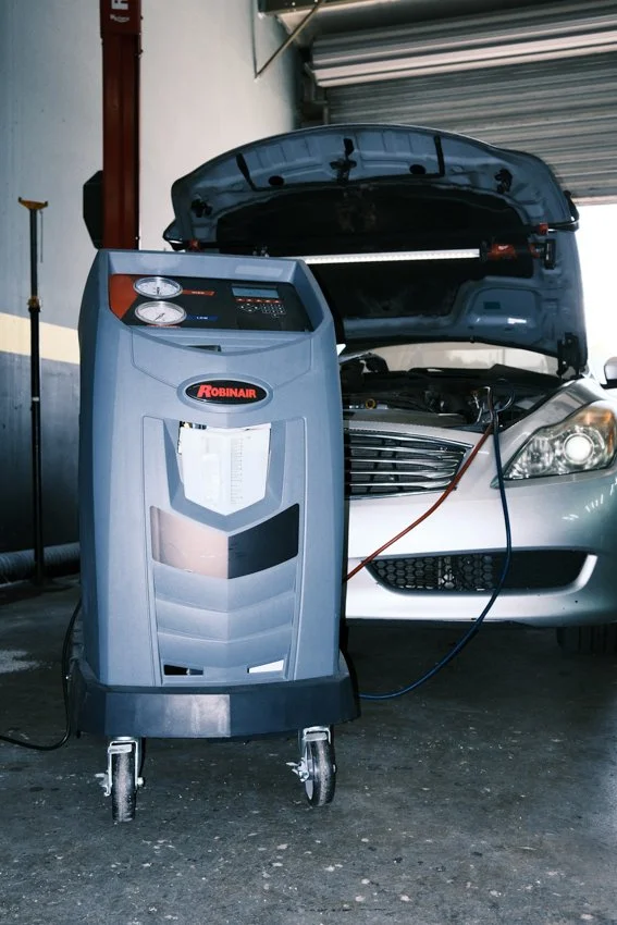 an air conditioning service machine is hooked up to an Infiniti automobile to fill the system with refrigerant gas