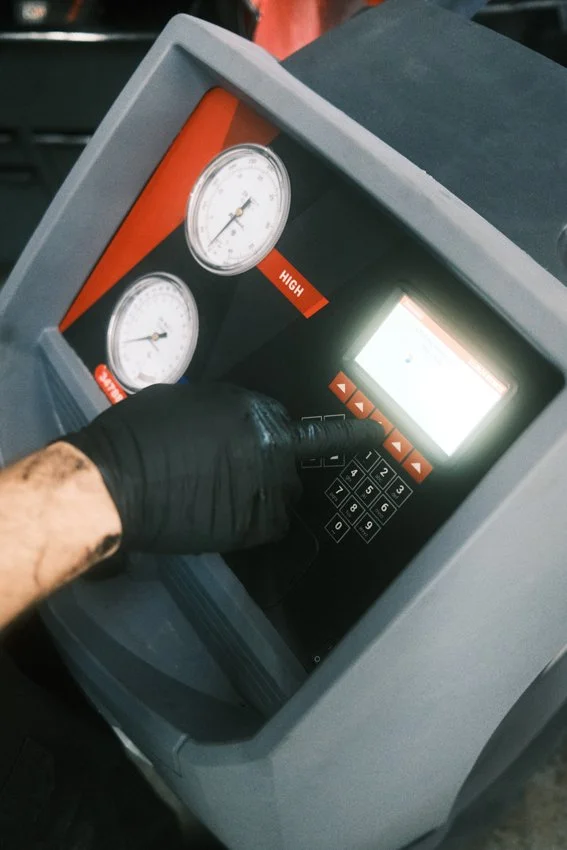 A mechanic is adjusting the settings of an air conditioning service machine