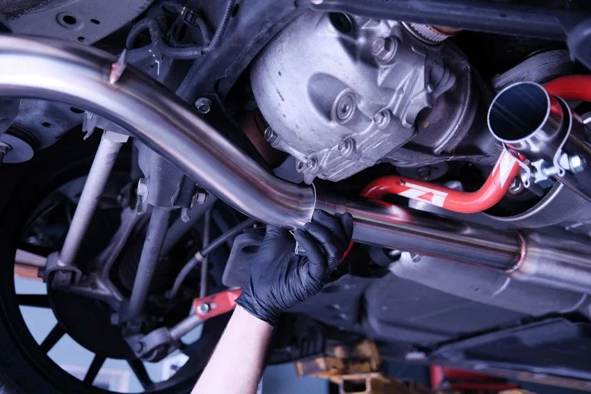 An Automotive technician is removing the car's exhaust in order to better access the transmission