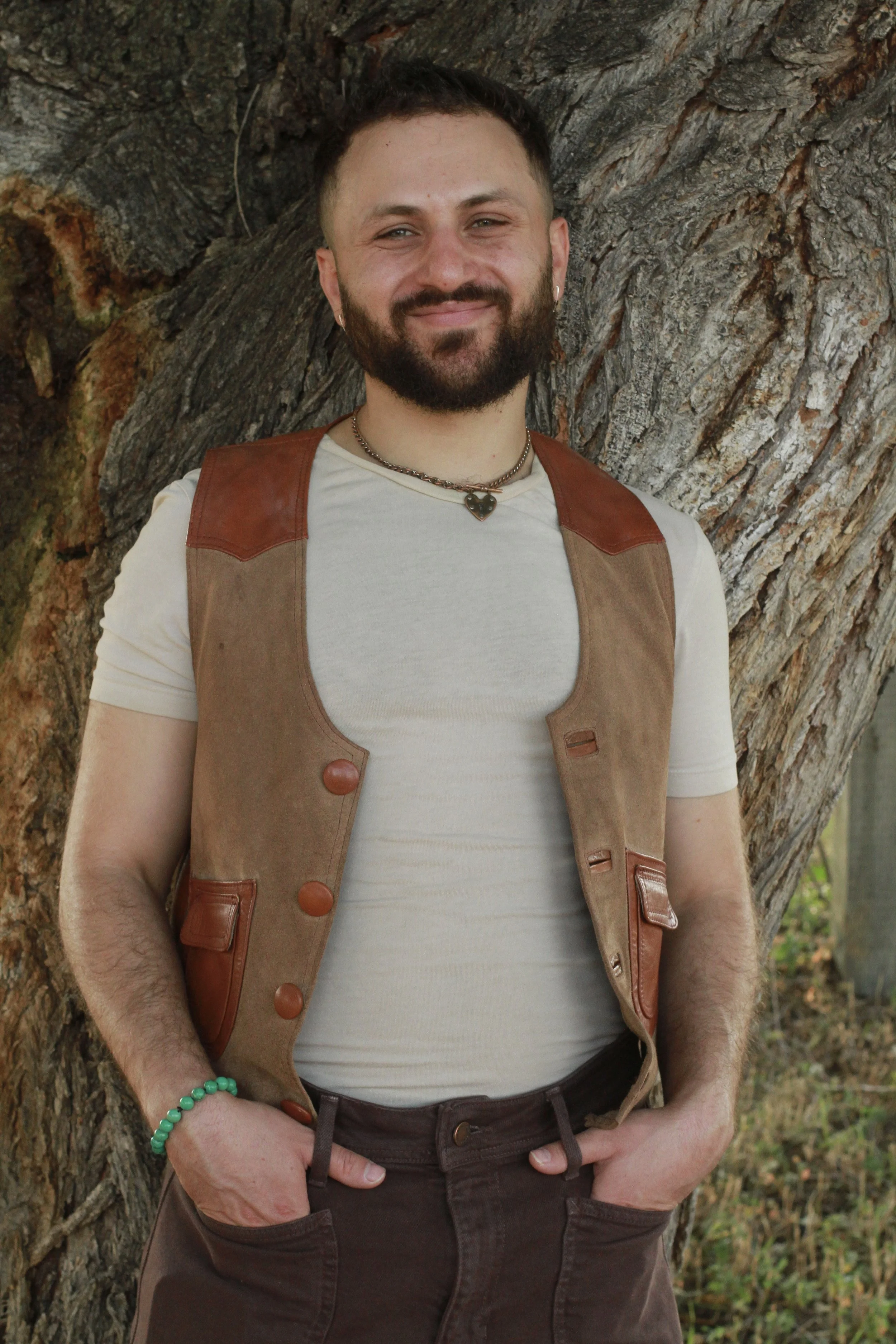 [Image] A queer male brown jacket smiling in front of tree, symbolizing offering LGBTQIA+ affirming therapy in Denver CO Blooming Moonlight Therapy.