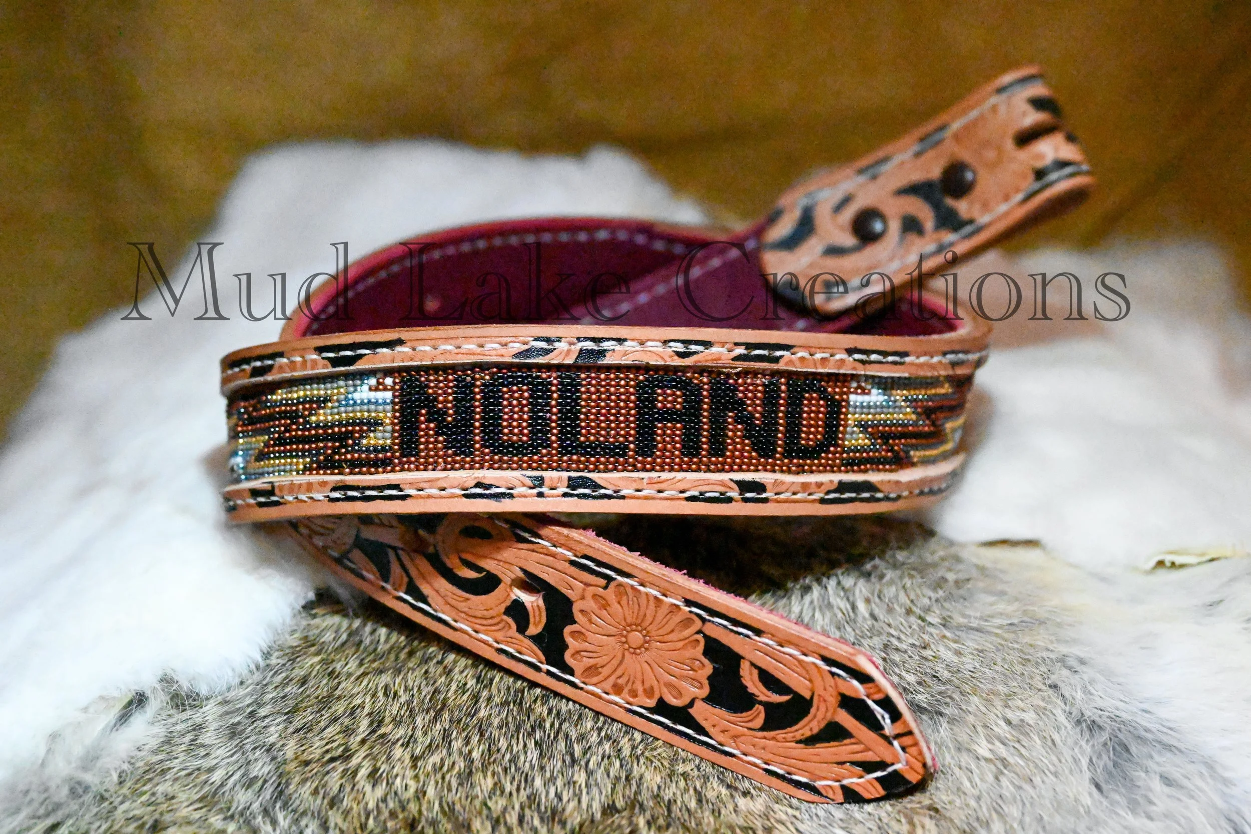 Close-up of a leather belt with detailed beadwork and embossed floral designs, resting on a soft, furry surface.