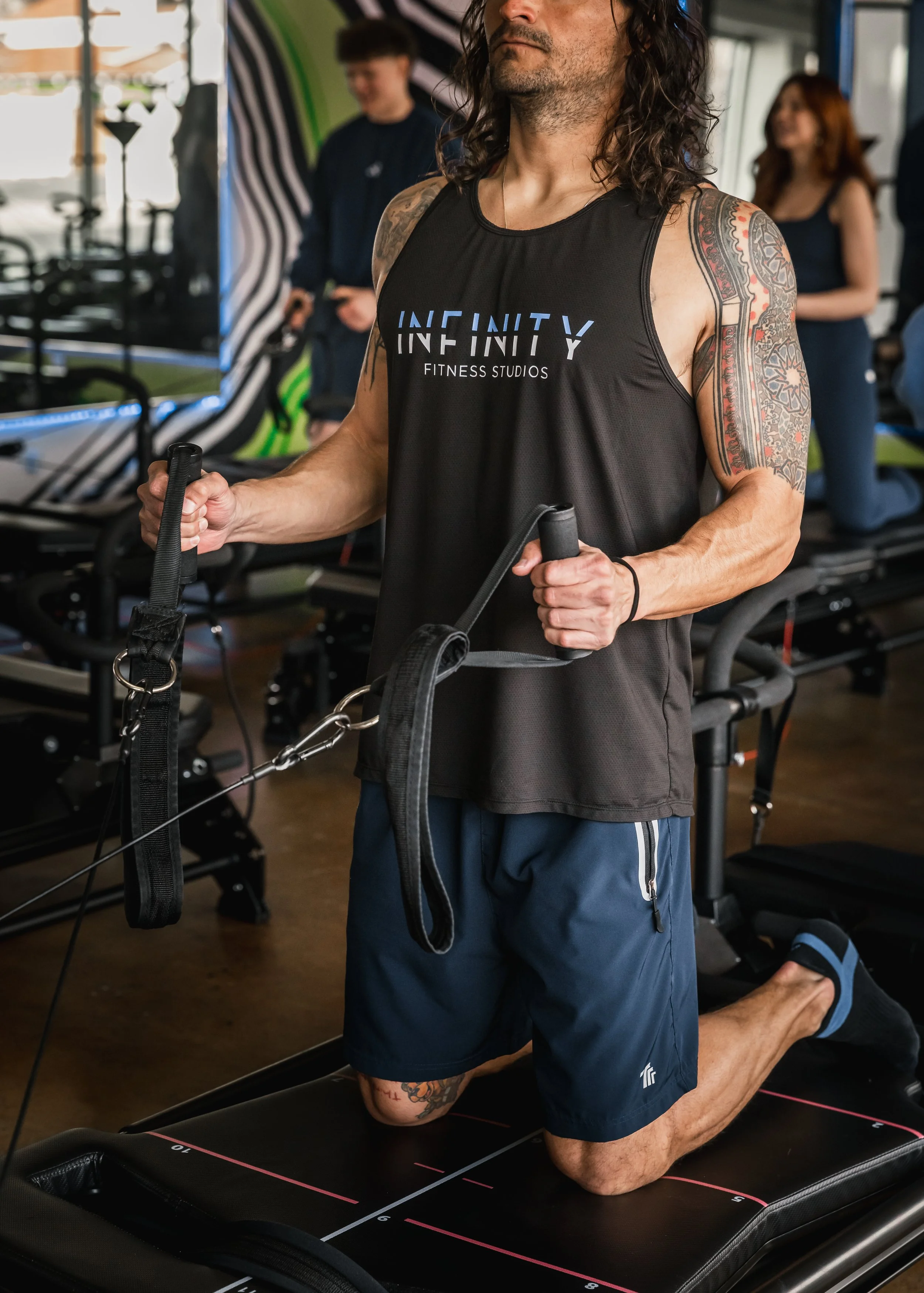 A person in athletic clothing kneeling at a gym, using resistance bands during a workout at Infinity Fitness Studios in Reno