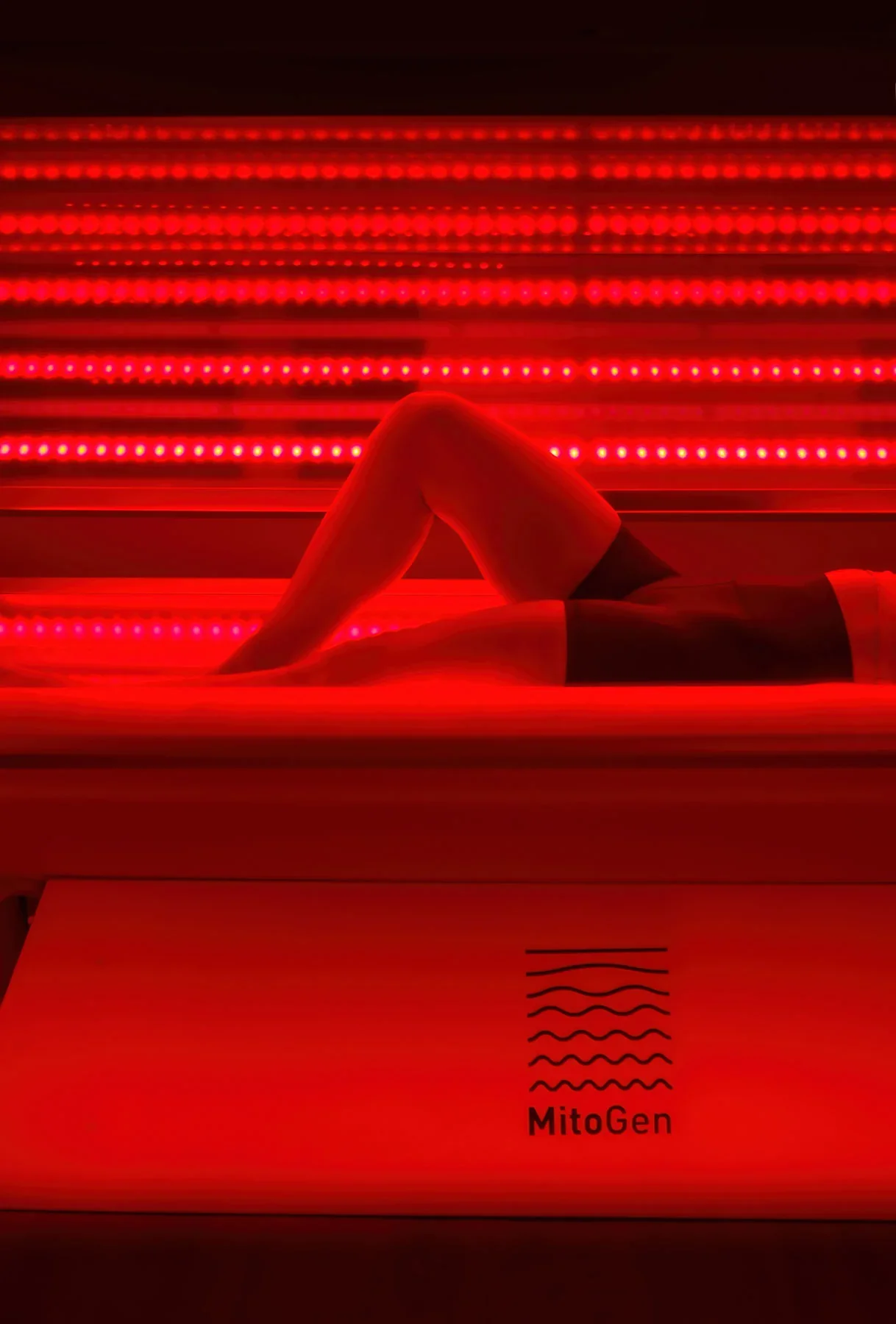 Person lying on a bed inside a red LED light therapy room at Infinity Fitness Studios in Reno NV