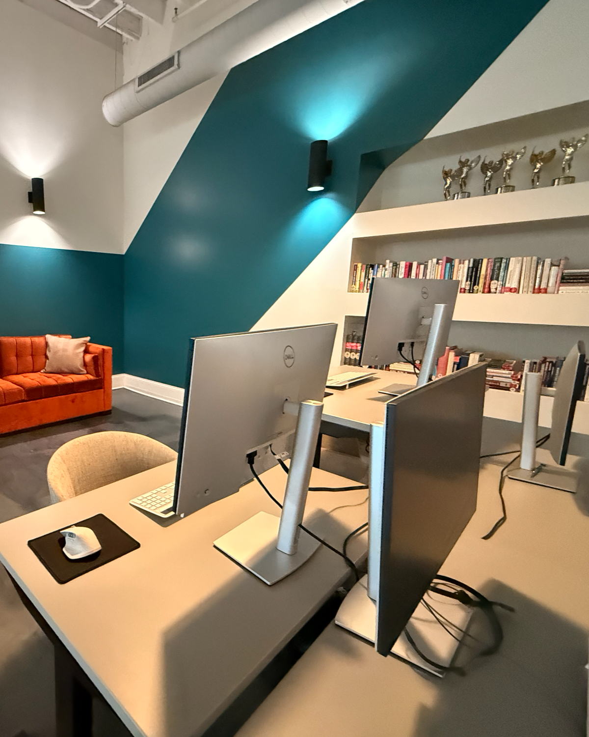 Chicago Agency Loft Workspace with Teal Accent Wall, Built-In Bookshelves, and Awards Display