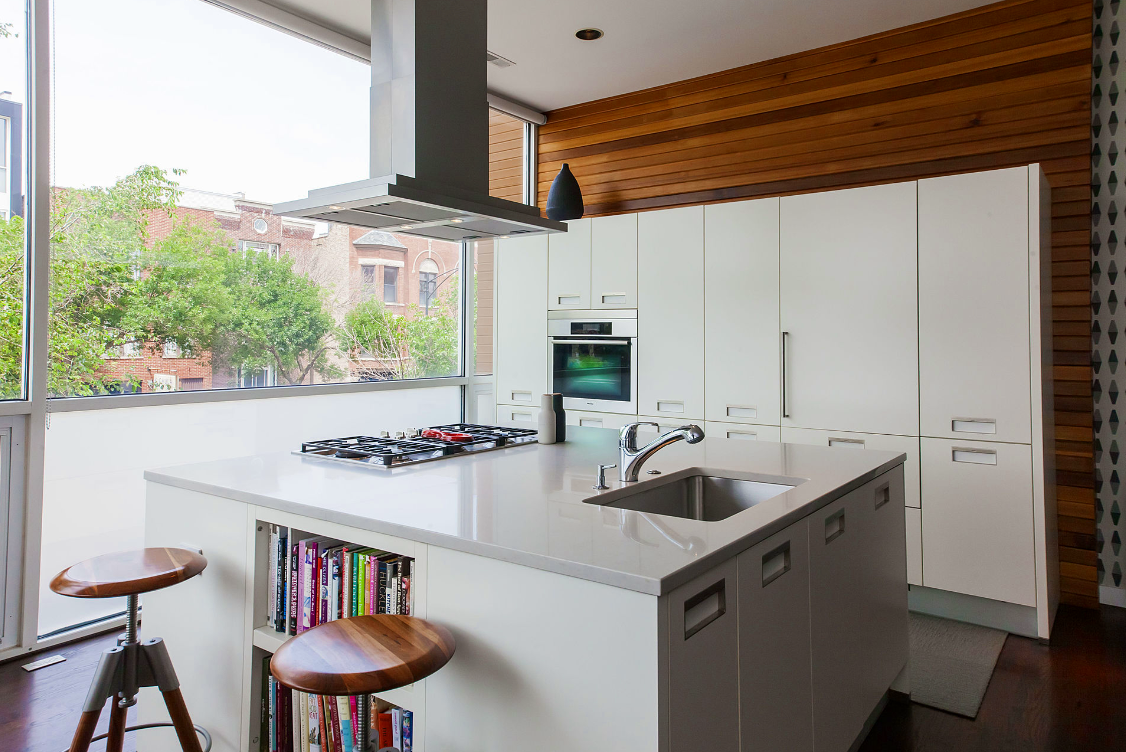 Sleek white kitchen with custom cabinetry, wood accents, and expansive windows overlooking Wicker Park, blending mid-century clarity with modern function