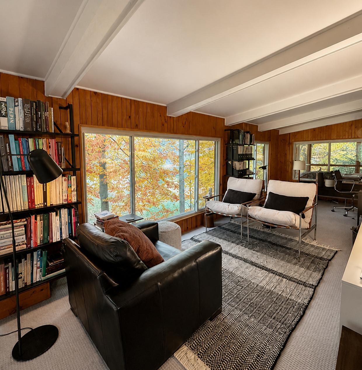 Open-concept loft living area with wood beams and treetop views, Fennville mid-century renovation