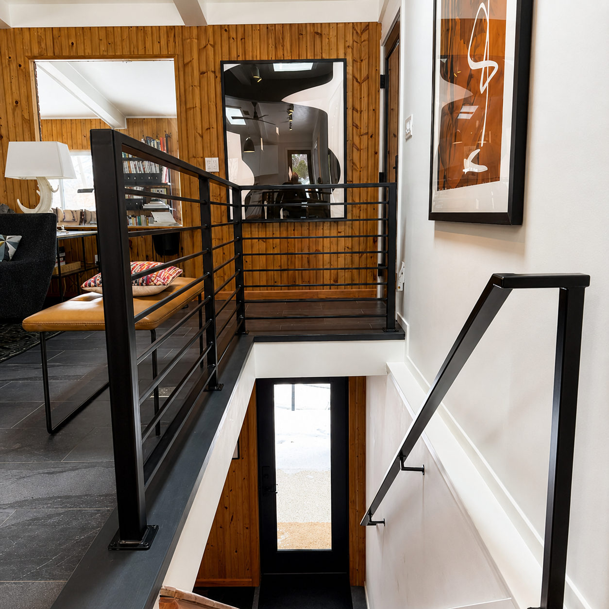 Clean lines, warm wood paneling, and sleek black steel railings define this light-filled stair hall. Thoughtful details and modern materials create a striking architectural transition that seamlessly connects the home's contemporary living spaces.