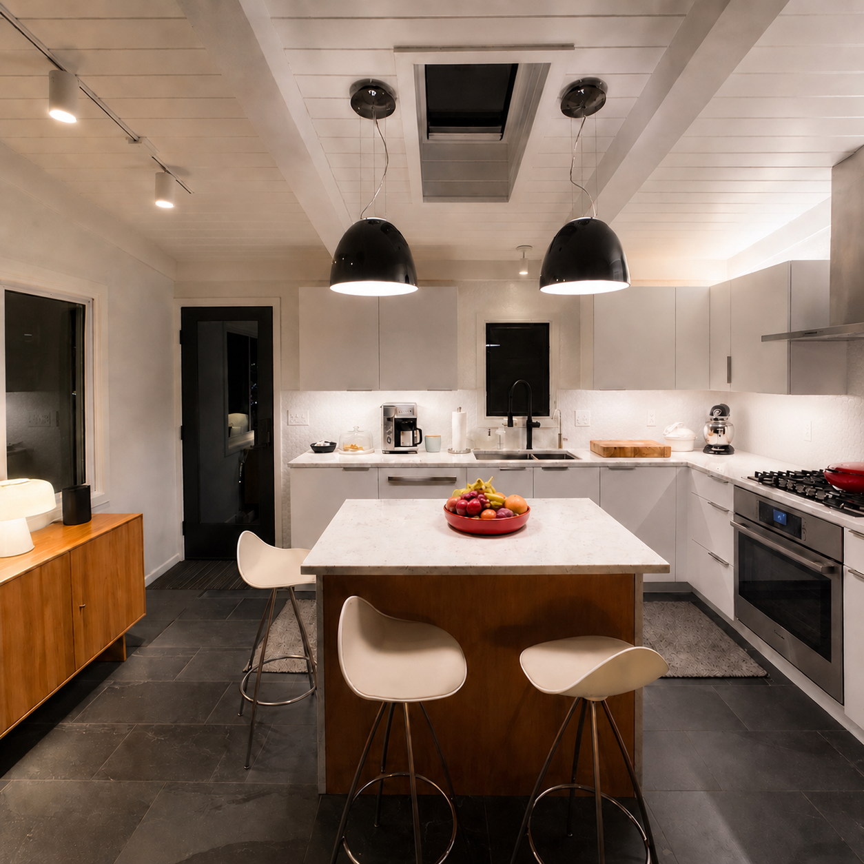 Modern white kitchen with wood island, black pendant lighting, and dark tile flooring — Fennville mid-century renovation