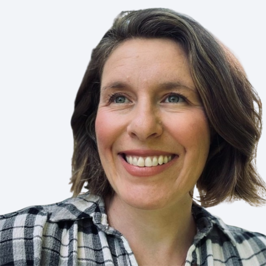 A woman with shoulder-length brown hair, wearing a black and white plaid shirt, smiling.